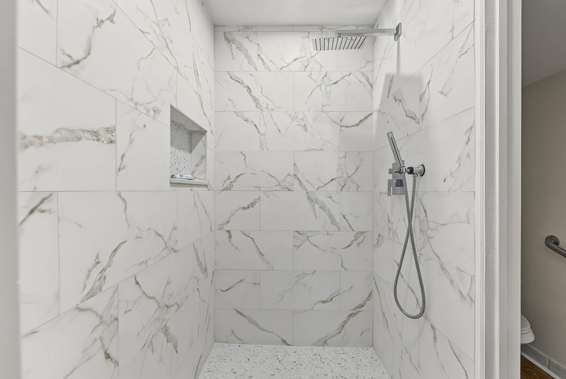 21109 NE 3RD Court, Miami, FL 33179 Walk-in shower featuring large-format white stone-finish wall tiling with grey veining, a built-in recessed niche, a ceiling-mounted rainfall showerhead, a separate handheld shower wand, and a textured white floor tiling