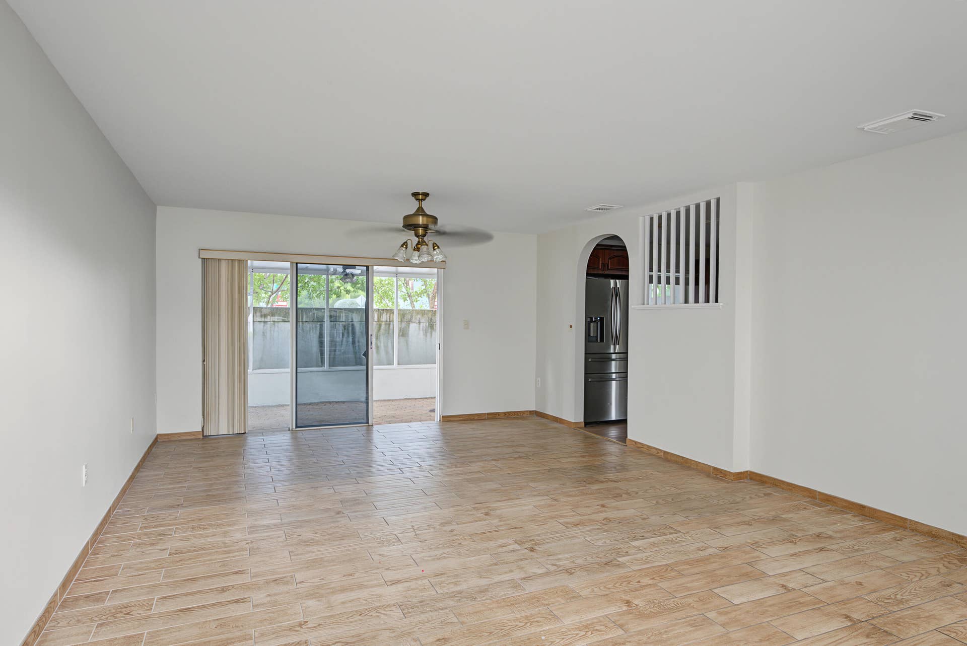 21109 NE 3RD Court, Miami, FL 33179 Neutral interior featuring wood-finish tile flooring, ceiling fan with integrated lighting, sliding glass door, arched doorway, and decorative spindle partition