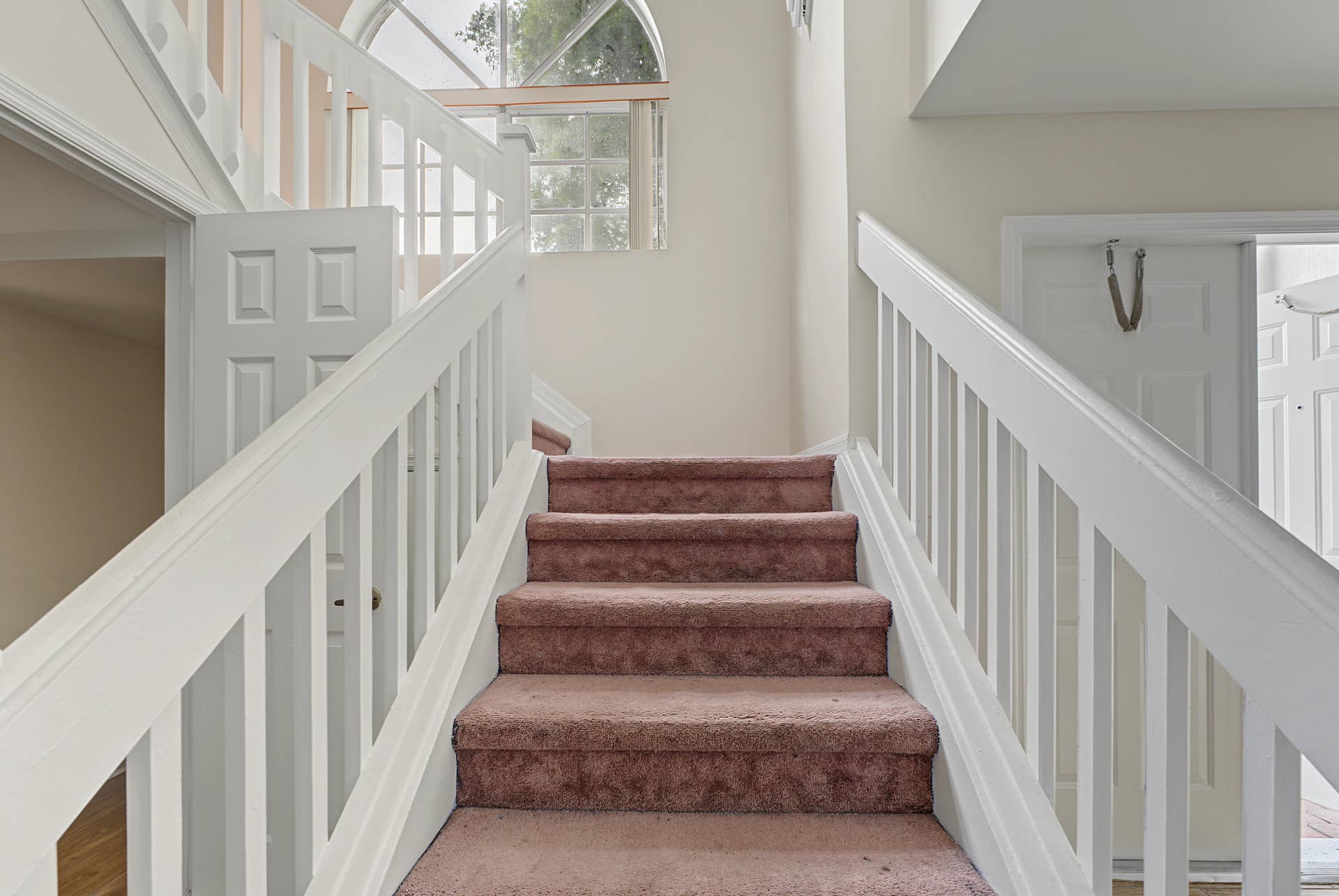 21109 NE 3RD Court, Miami, FL 33179 Staircase featuring white balusters and handrails with an arched window