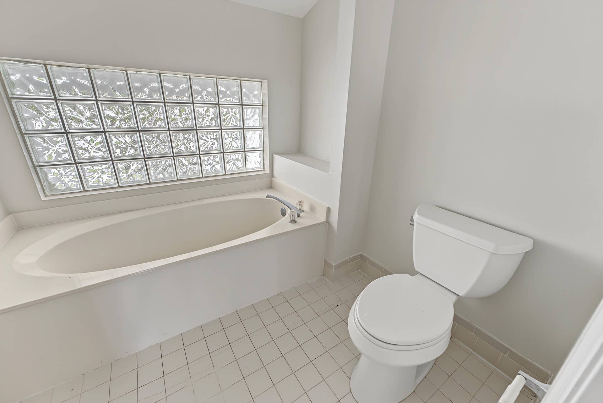 21109 NE 3RD Court, Miami, FL 33179 Oval soaking tub with integrated deck, glass block window, chrome plumbing fixtures, and ceramic tile flooring