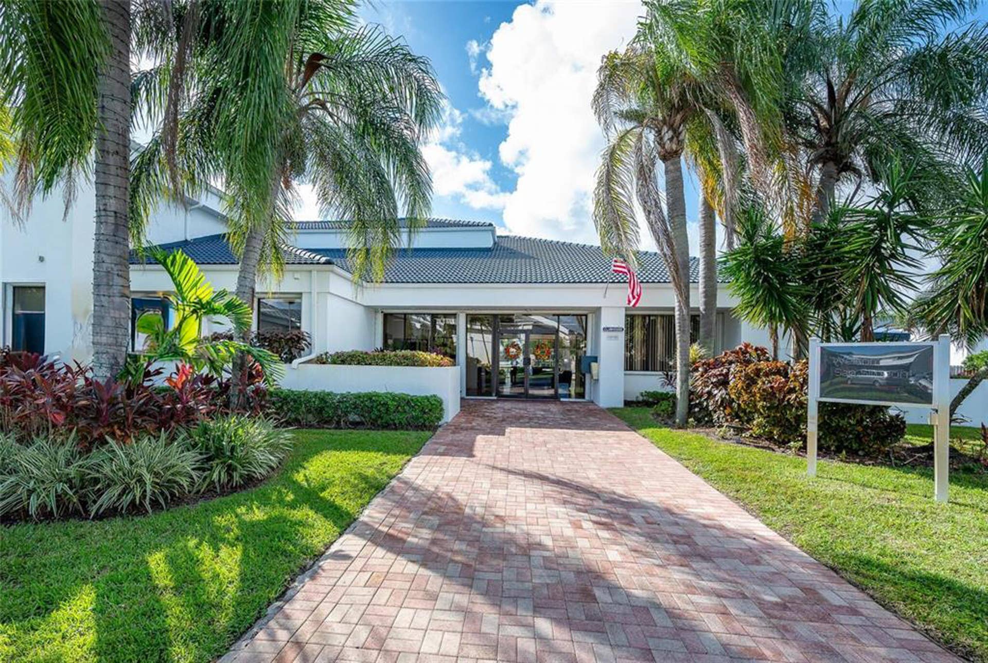 21109 NE 3RD Court, Miami, FL 33179 Exterior facade featuring a tile roof, glass-paneled double entry doors, brick paver walkway, and mature palm trees
