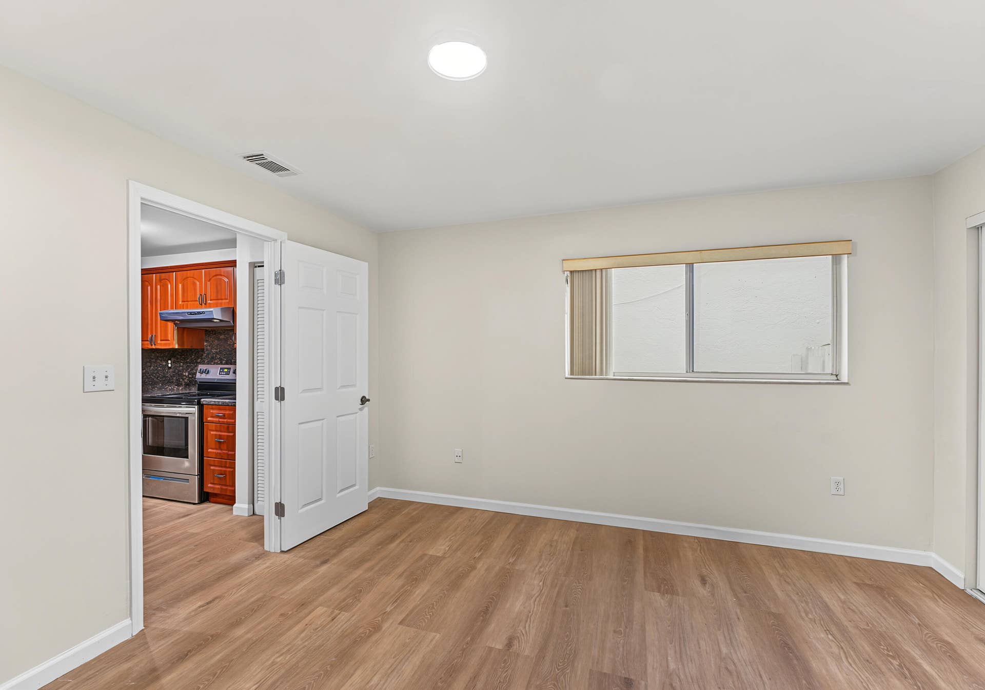 21109 NE 3RD Court, Miami, FL 33179 Neutral-toned interior space featuring wood-finish flooring, a recessed ceiling light, a sliding window with vertical blinds, and a white six-panel door