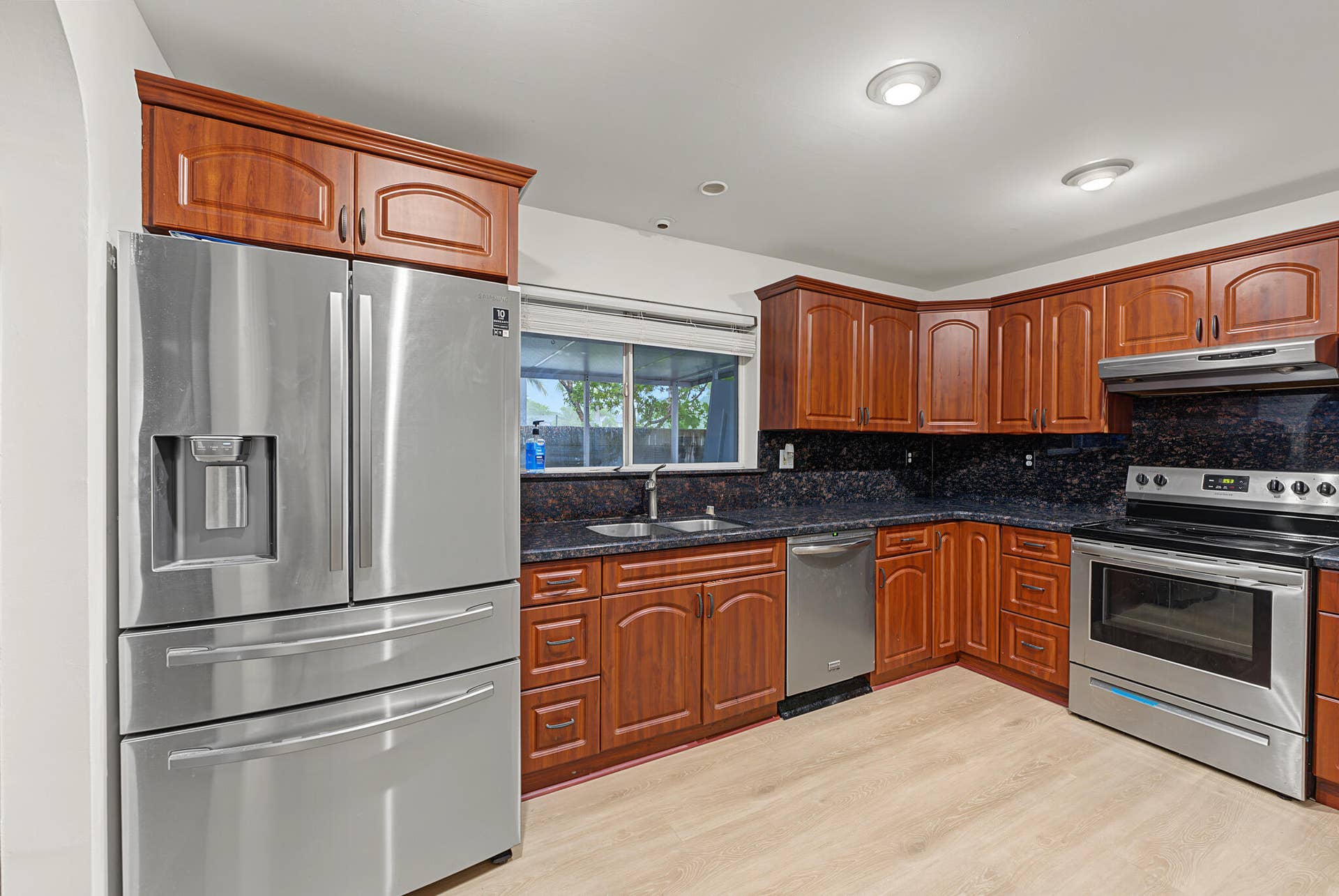 21109 NE 3RD Court, Miami, FL 33179 Kitchen featuring wood-finish cabinetry, stone-style countertops, stainless steel appliances, and wood-finish flooring