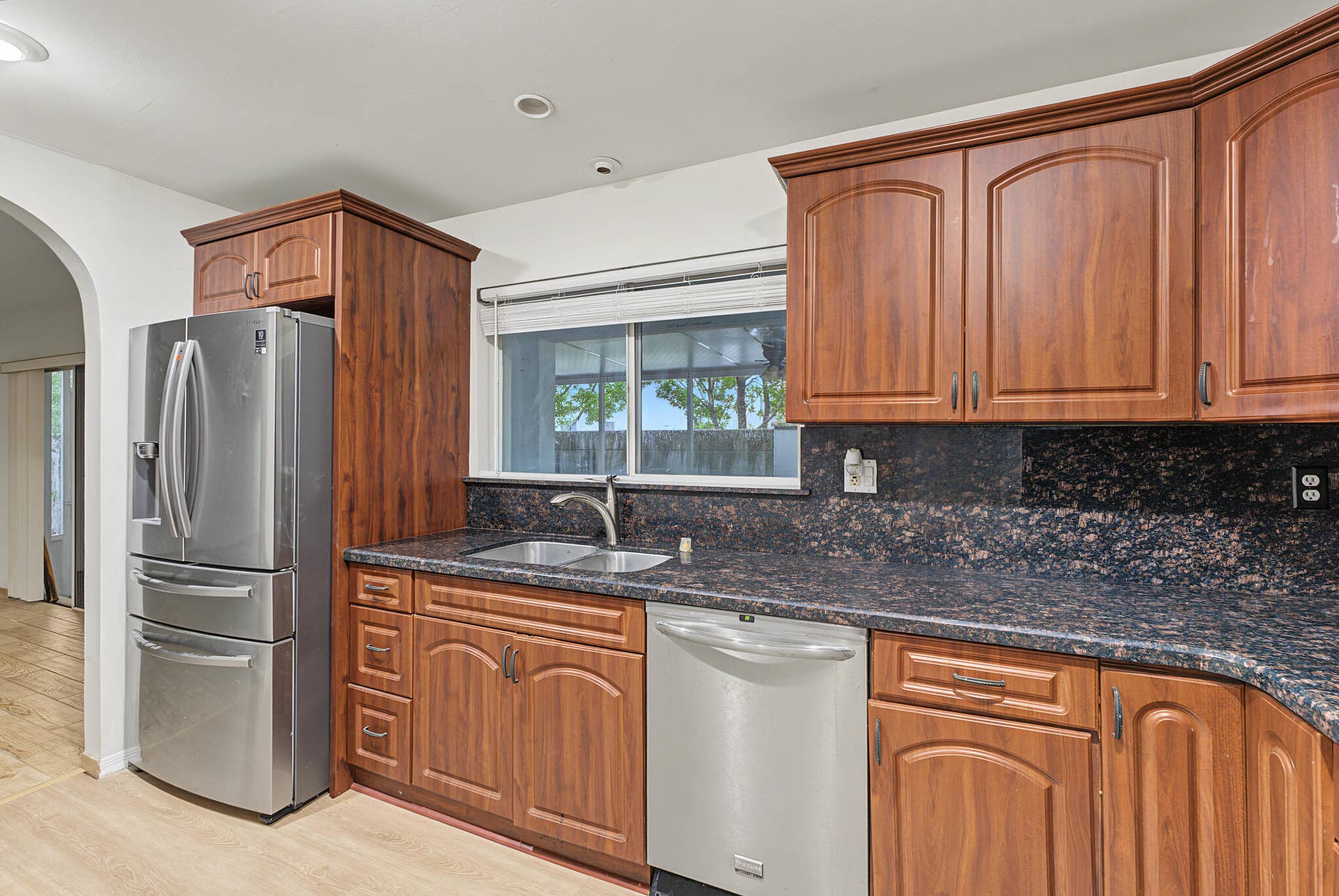 21109 NE 3RD Court, Miami, FL 33179 Kitchen featuring stained wood cabinetry, stone countertops, stainless steel appliances, a double-basin sink, and arched doorway