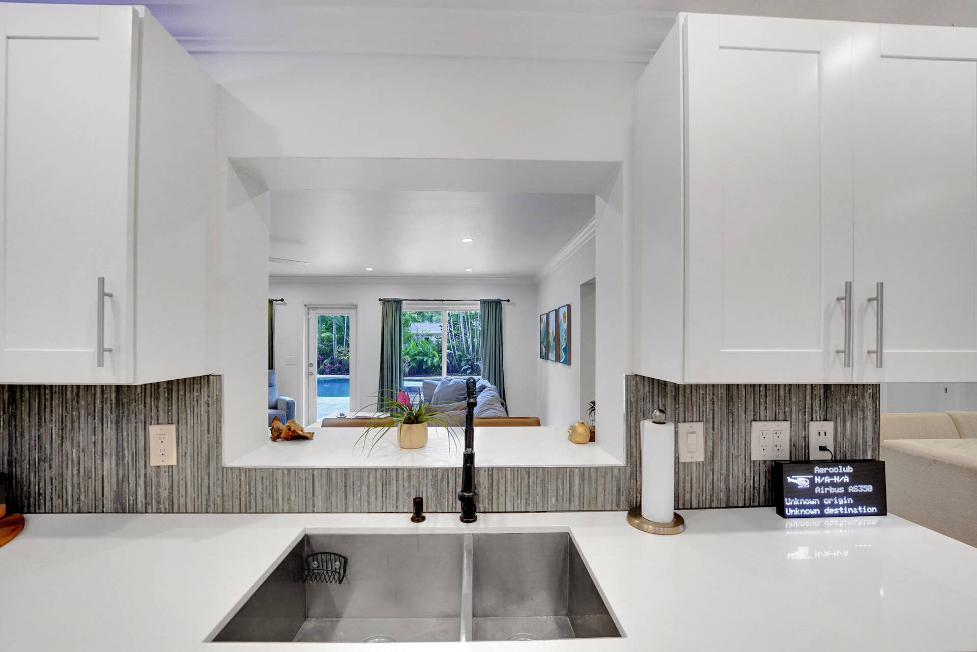 380 NW 35TH Court, Oakland Park, FL 33309 Kitchen featuring white shaker-style cabinetry, solid-surface countertops, a dual-basin stainless steel sink, matte black gooseneck faucet, and textured tile backsplash