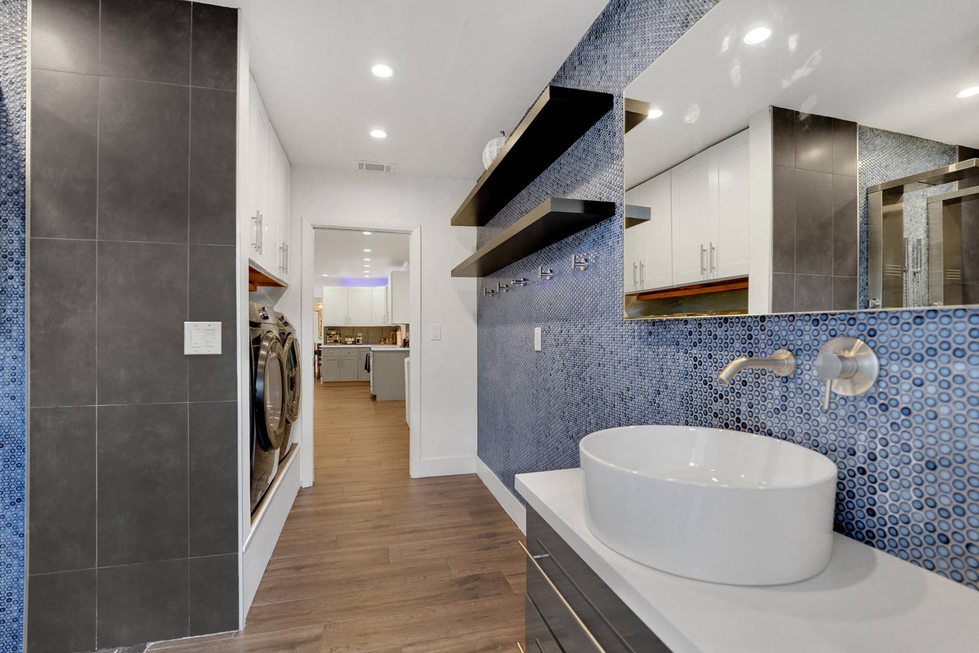 380 NW 35TH Court, Oakland Park, FL 33309 Vessel sink with a wall-mounted faucet, custom vanity with a quartz countertop, blue circular mosaic tile backsplash, built-in floating shelves