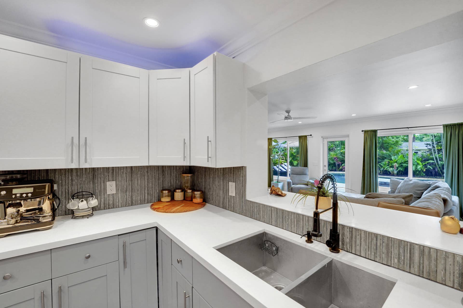 380 NW 35TH Court, Oakland Park, FL 33309 Kitchen featuring white upper cabinetry, grey lower cabinetry, white countertops, a textured tile backsplash, and a dual-basin stainless steel sink with a high-arch matte black faucet