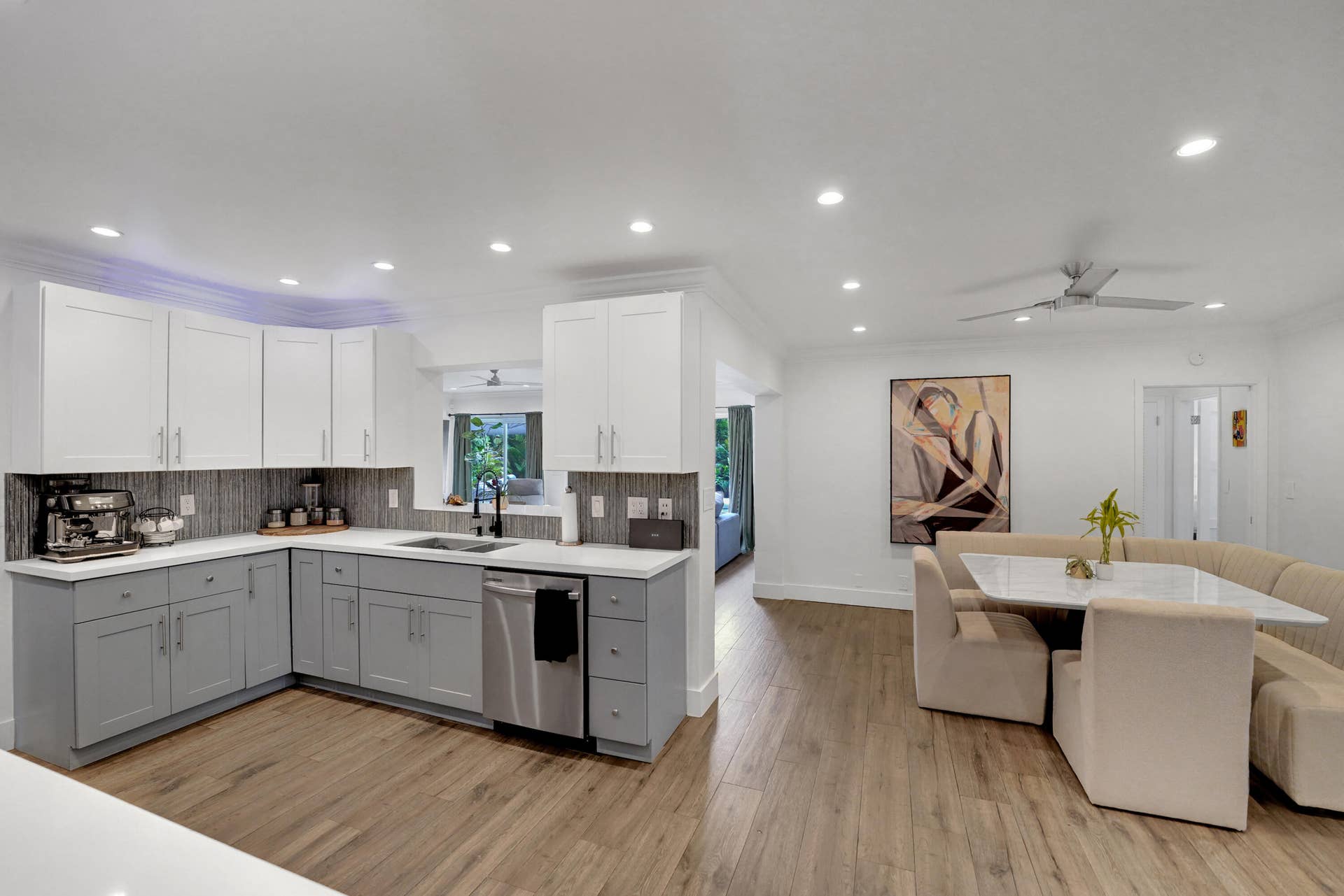 380 NW 35TH Court, Oakland Park, FL 33309 Kitchen featuring two-tone shaker-style cabinetry, quartz countertops, tile backsplash, stainless steel dishwasher.