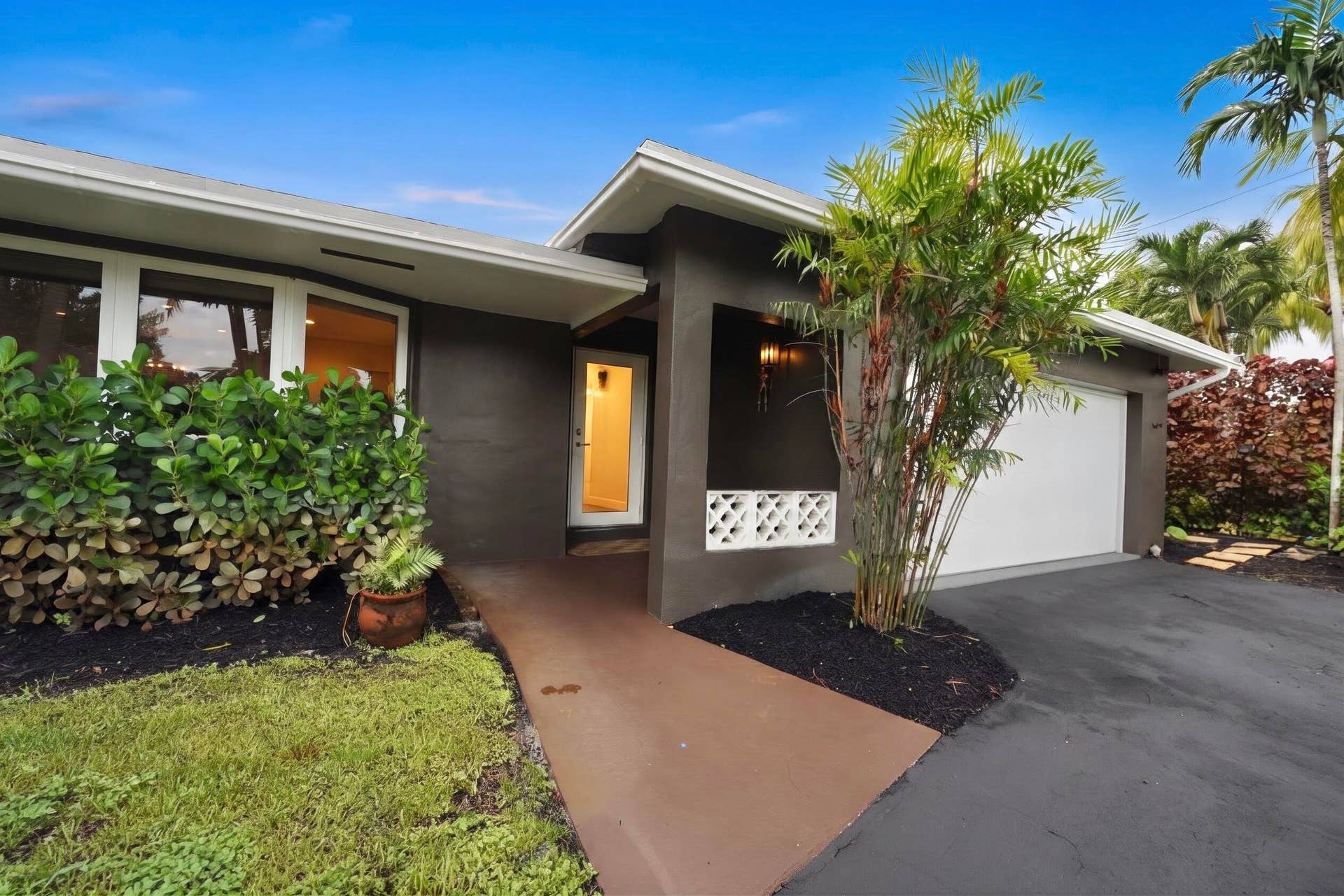 380 NW 35TH Court, Oakland Park, FL 33309 Stucco exterior facade featuring a covered entryway, decorative breeze block accents, oversized windows, and a paved driveway