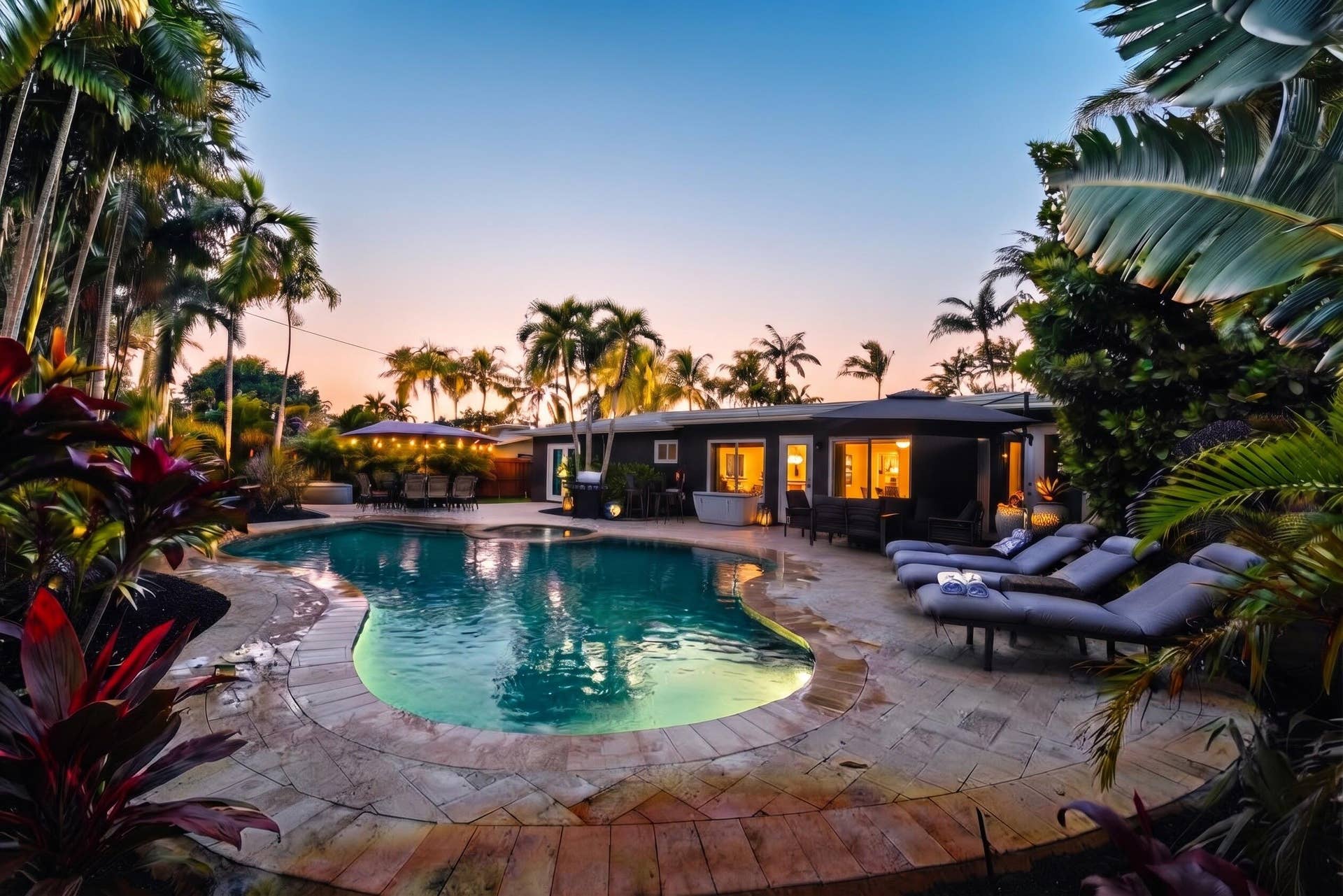 380 NW 35TH Court, Oakland Park, FL 33309 Freeform swimming pool with stone coping, expansive paver patio, integrated spa, and mature tropical landscaping