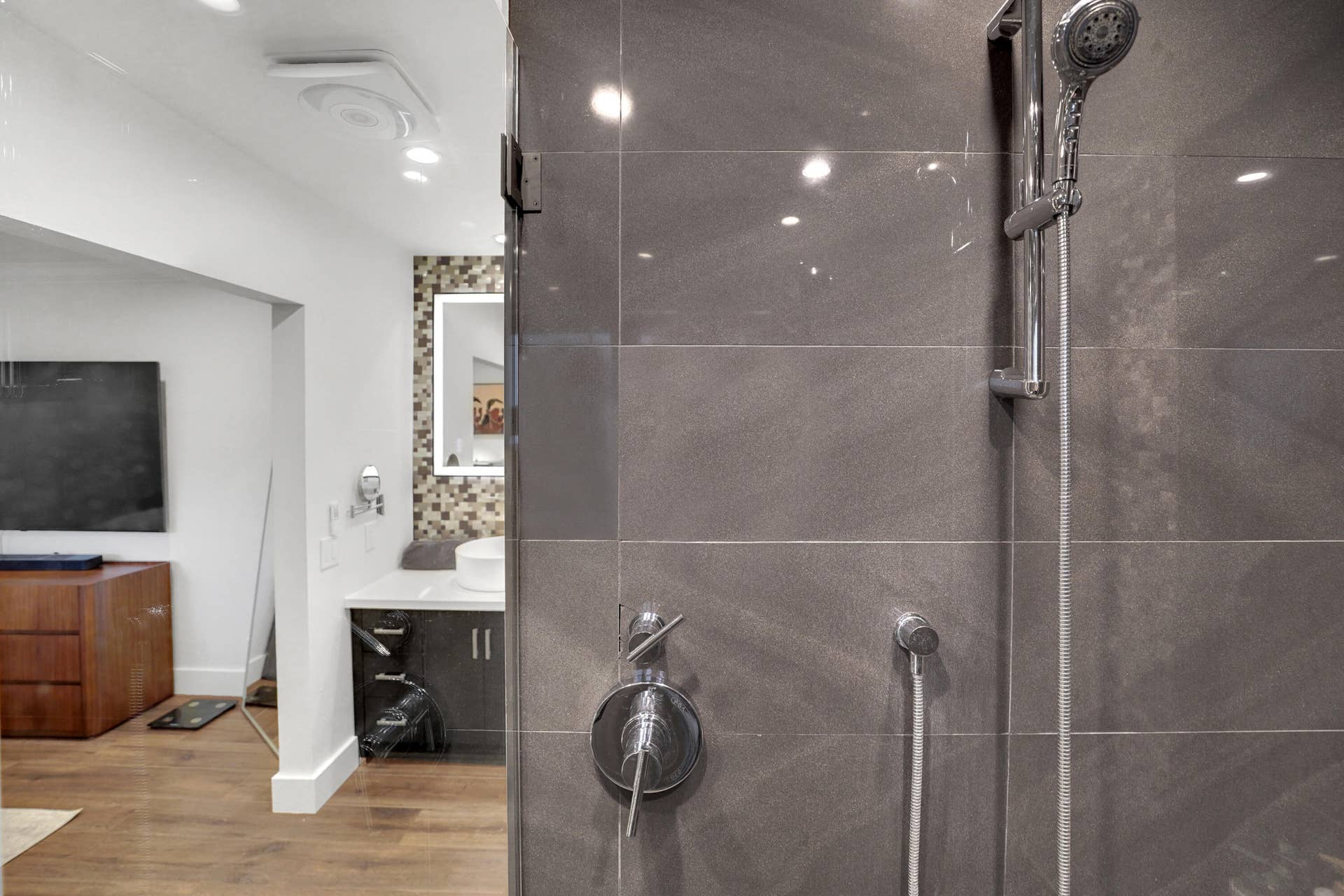 380 NW 35TH Court, Oakland Park, FL 33309 Shower enclosure featuring large-format grey tile, a chrome handheld shower head, and integrated single-handle temperature control