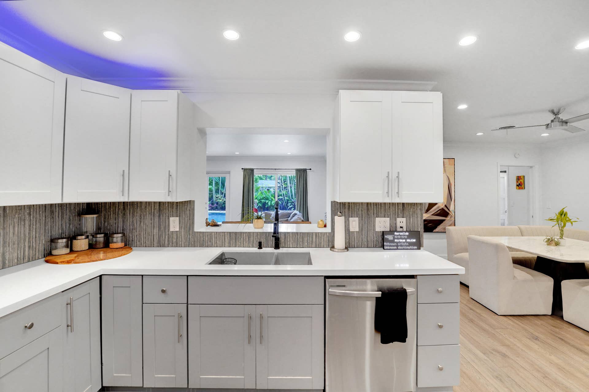 380 NW 35TH Court, Oakland Park, FL 33309 Kitchen featuring white upper cabinetry, grey lower cabinetry, white countertops, stainless steel dishwasher, and textured tile backsplash