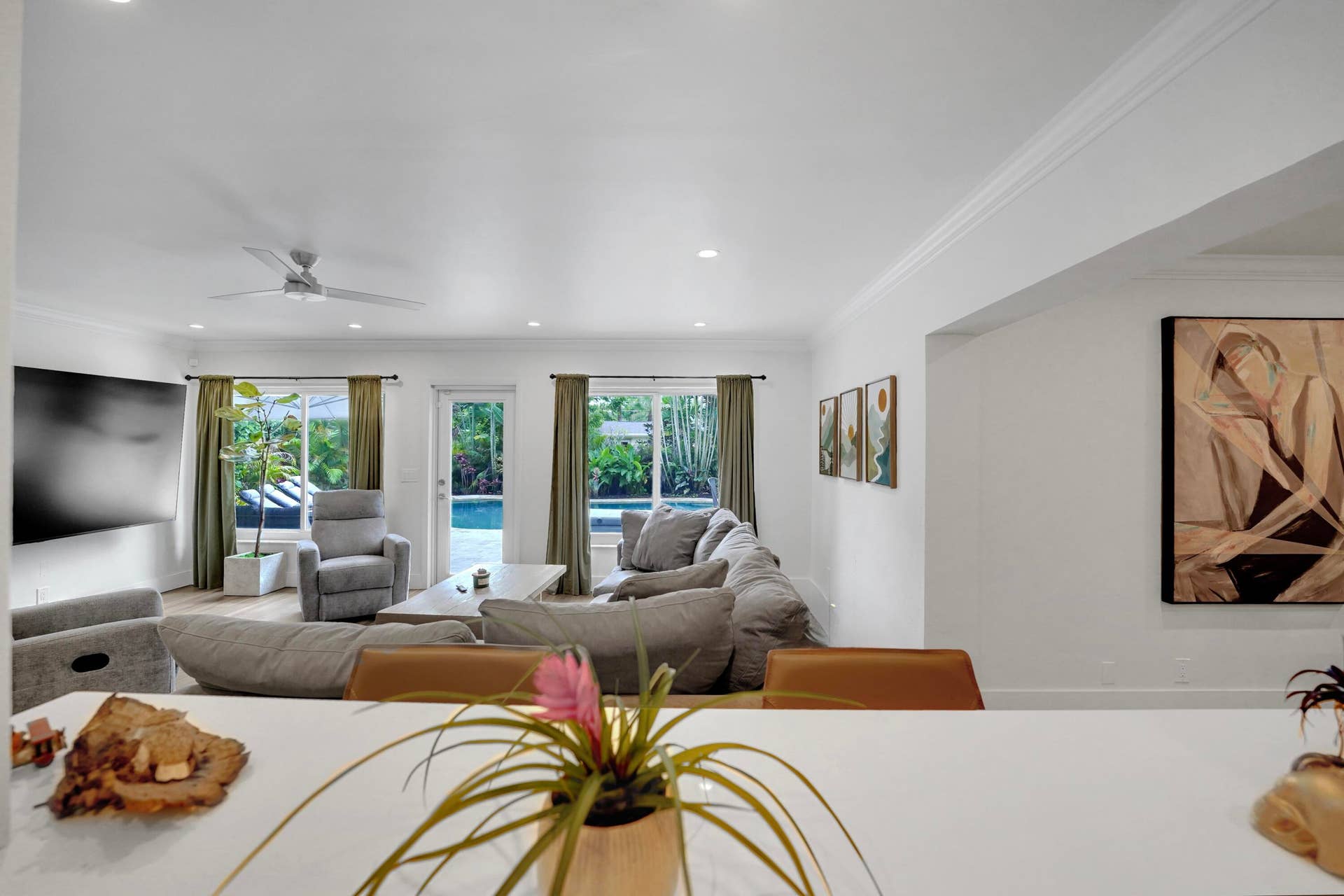 380 NW 35TH Court, Oakland Park, FL 33309 Open-concept interior featuring recessed lighting, crown molding, a white countertop peninsula, and multiple windows with exterior pool access
