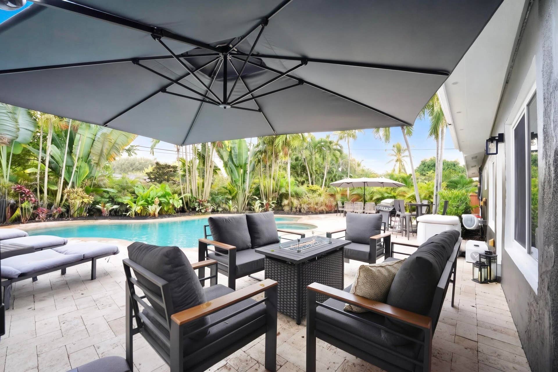 380 NW 35TH Court, Oakland Park, FL 33309 Outdoor patio featuring stone paver flooring, custom in-ground pool, and mature palm landscaping