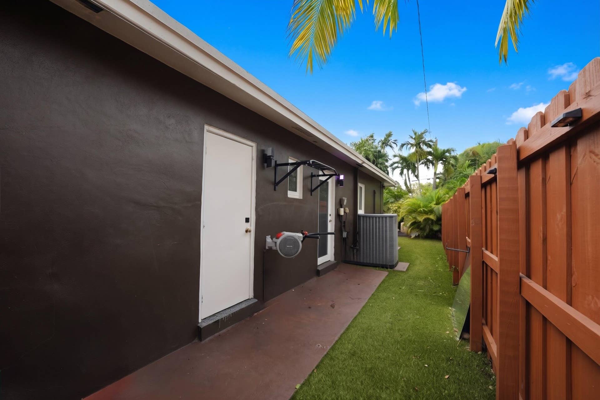 380 NW 35TH Court, Oakland Park, FL 33309 Exterior side yard featuring a concrete patio, synthetic turf lawn, and a solid wood privacy fence