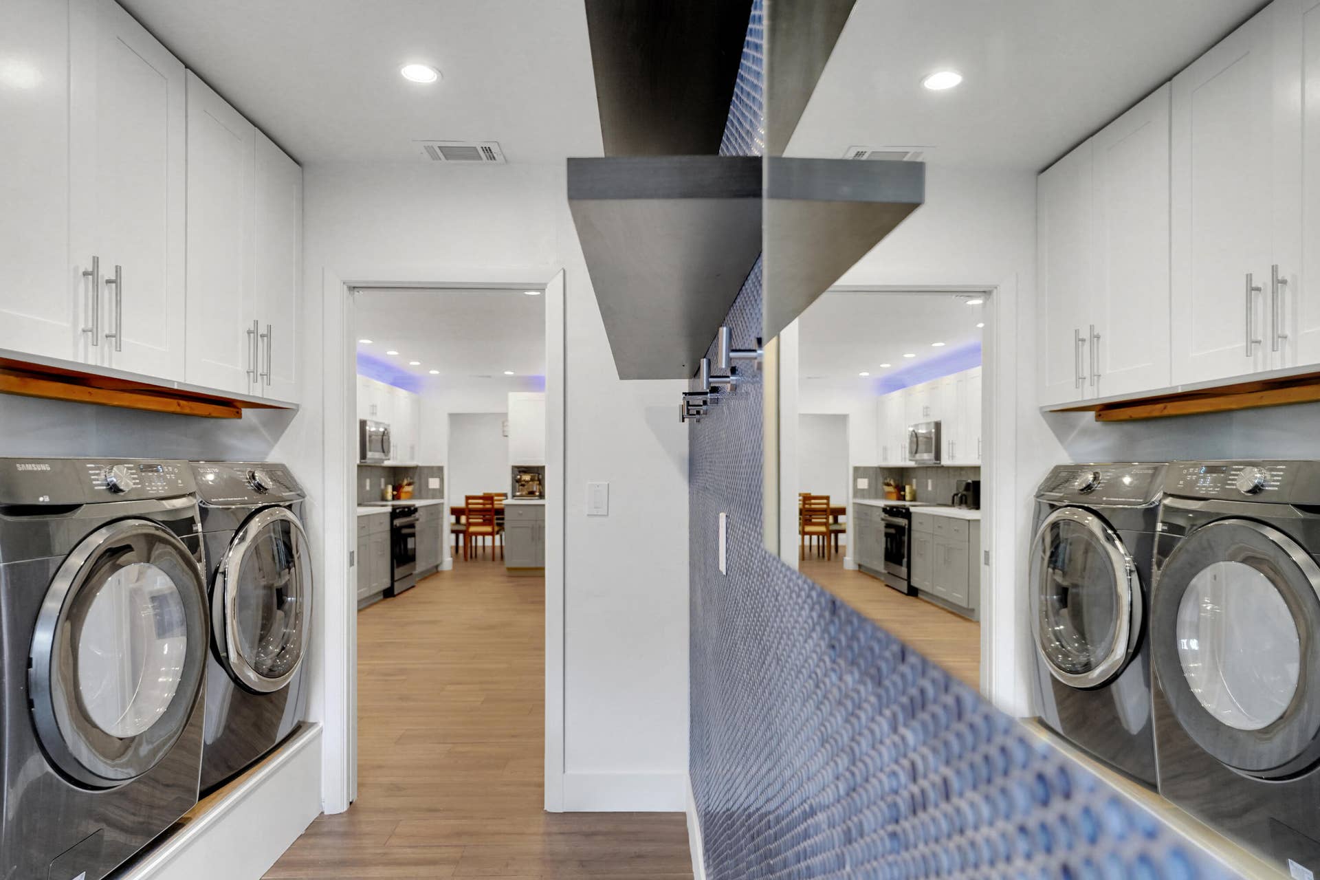 380 NW 35TH Court, Oakland Park, FL 33309 Laundry room featuring crisp white cabinetry with satin nickel pulls, a textured blue accent wall with built-in shelving.