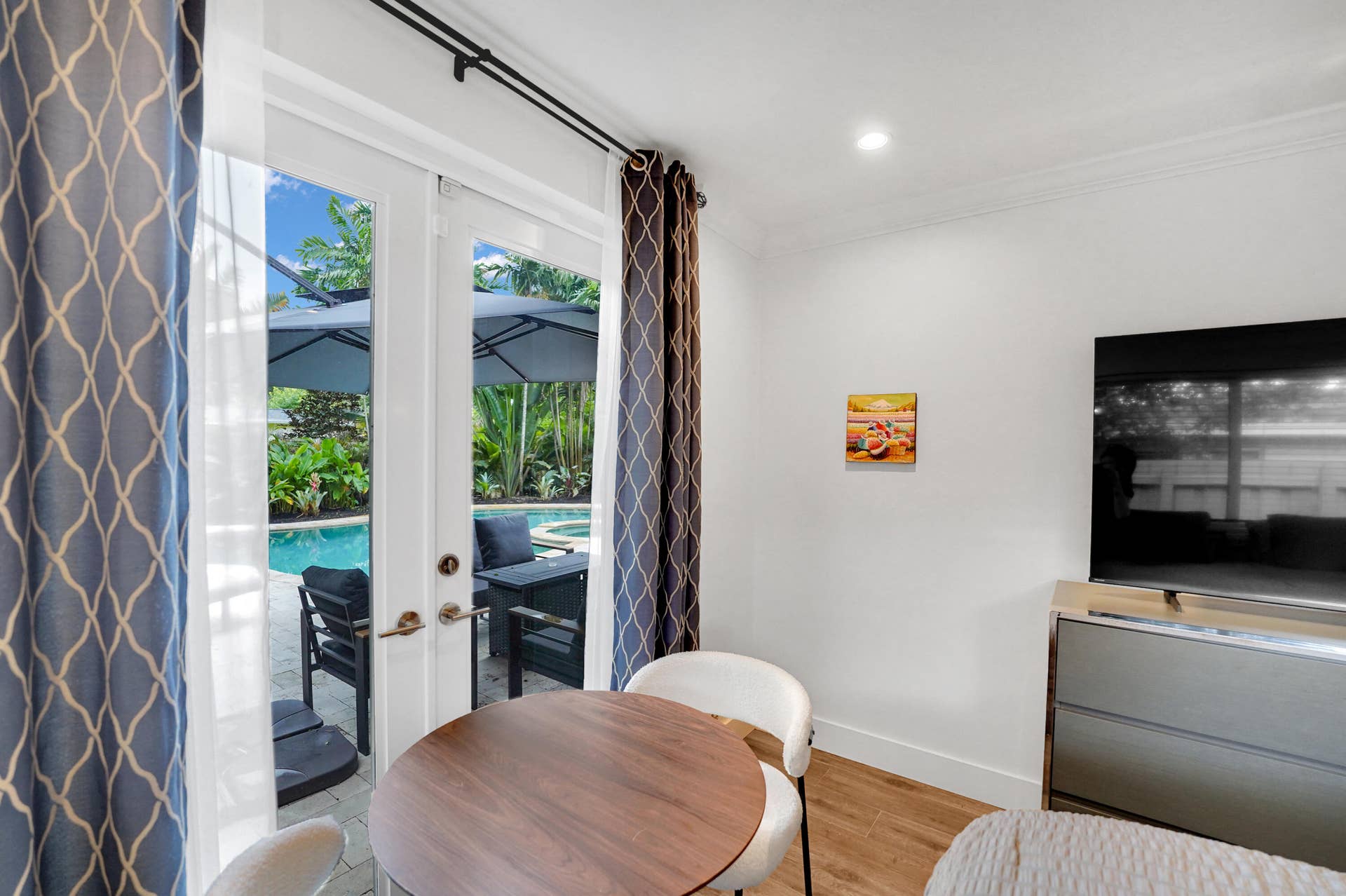 380 NW 35TH Court, Oakland Park, FL 33309 Glass-paned French doors opening to a paver patio, swimming pool, and lush landscaping