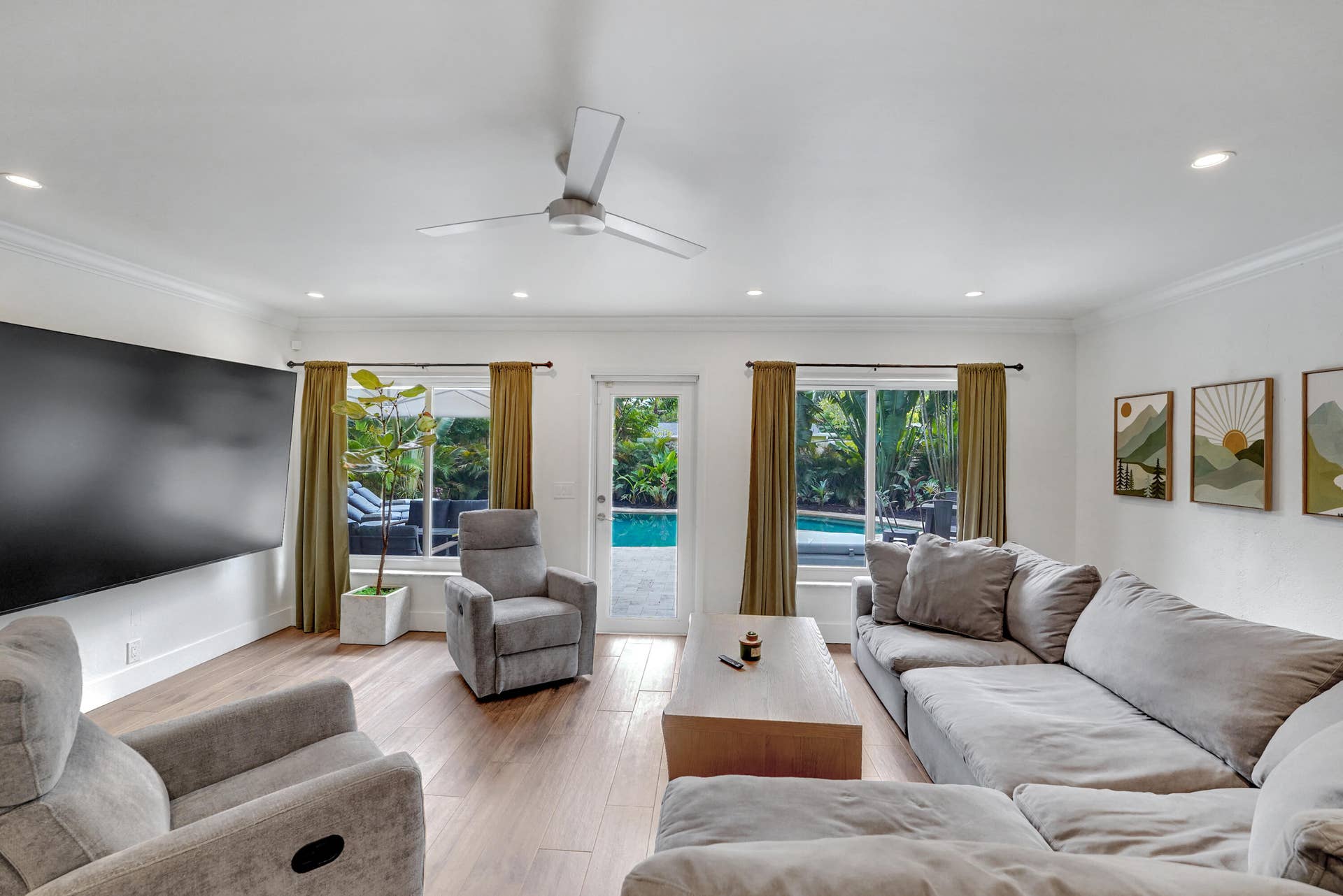 380 NW 35TH Court, Oakland Park, FL 33309 Living area recessed lighting, a modern ceiling fan, and access to a rear outdoor pool area via a glass-paneled door