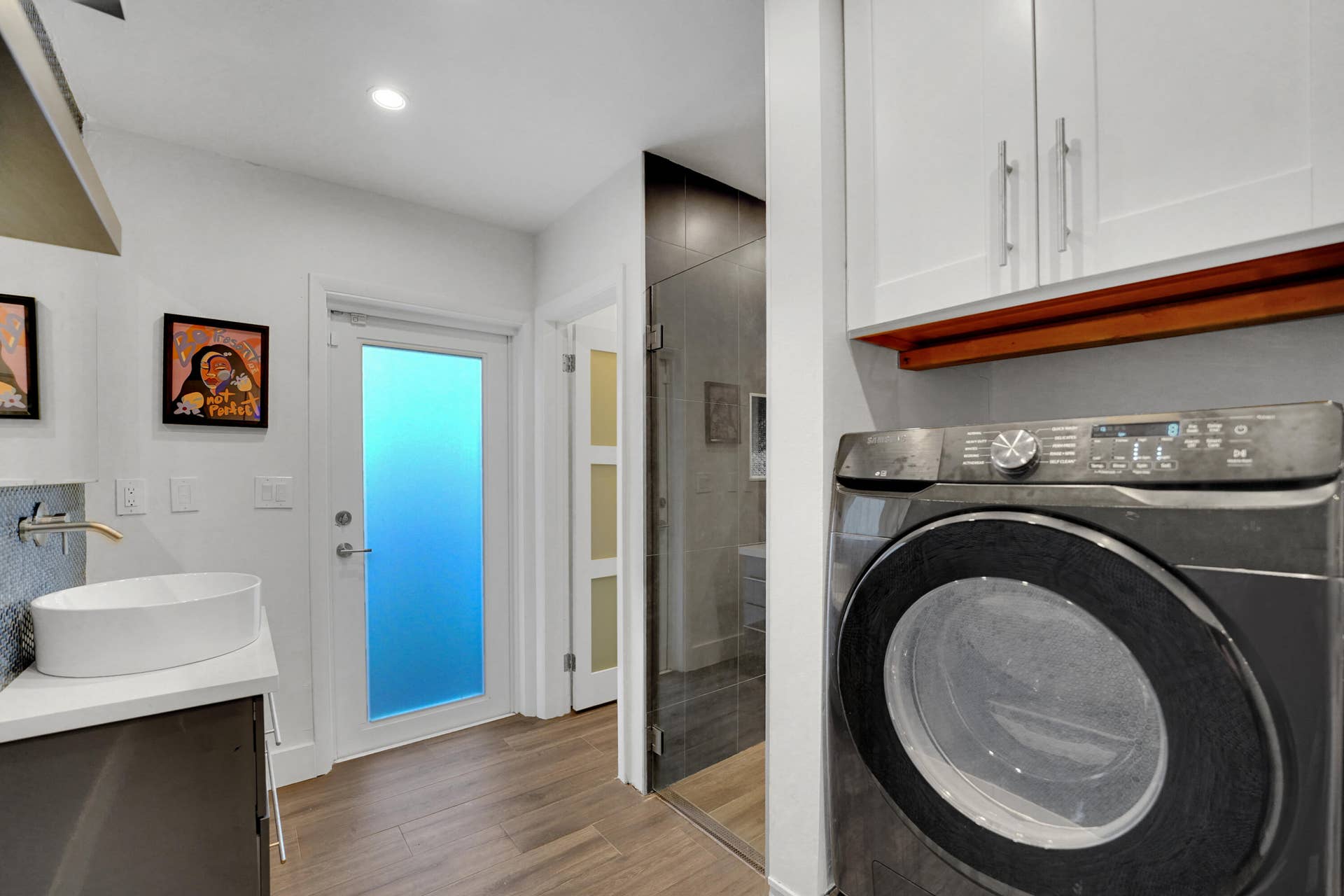 380 NW 35TH Court, Oakland Park, FL 33309 Utility space featuring a vessel sink with a wall-mounted faucet, white shaker-style cabinetry, and a frosted glass-panel door