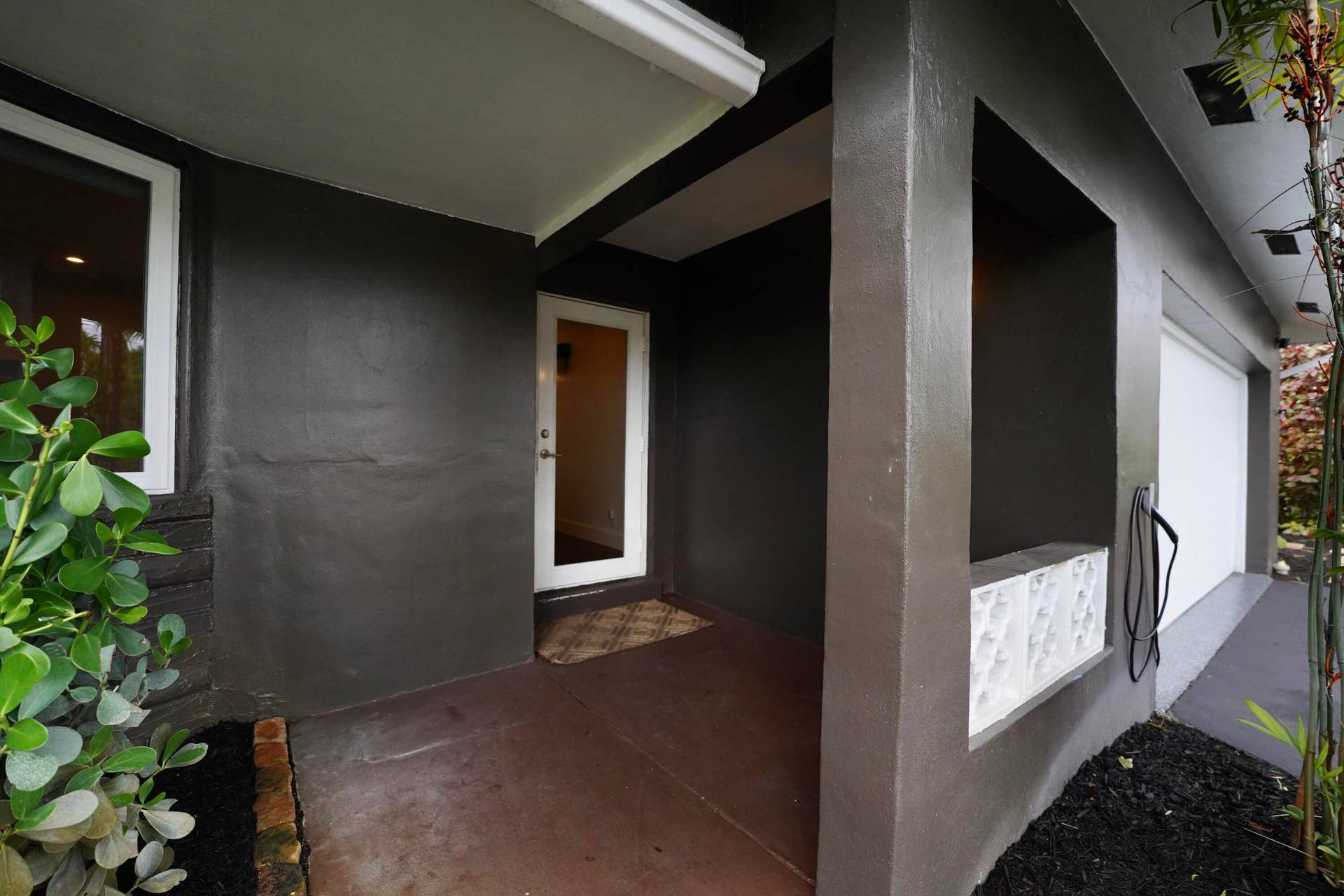 380 NW 35TH Court, Oakland Park, FL 33309 Covered entryway featuring a concrete porch, decorative patterned block screen, white entry door, and attached garage