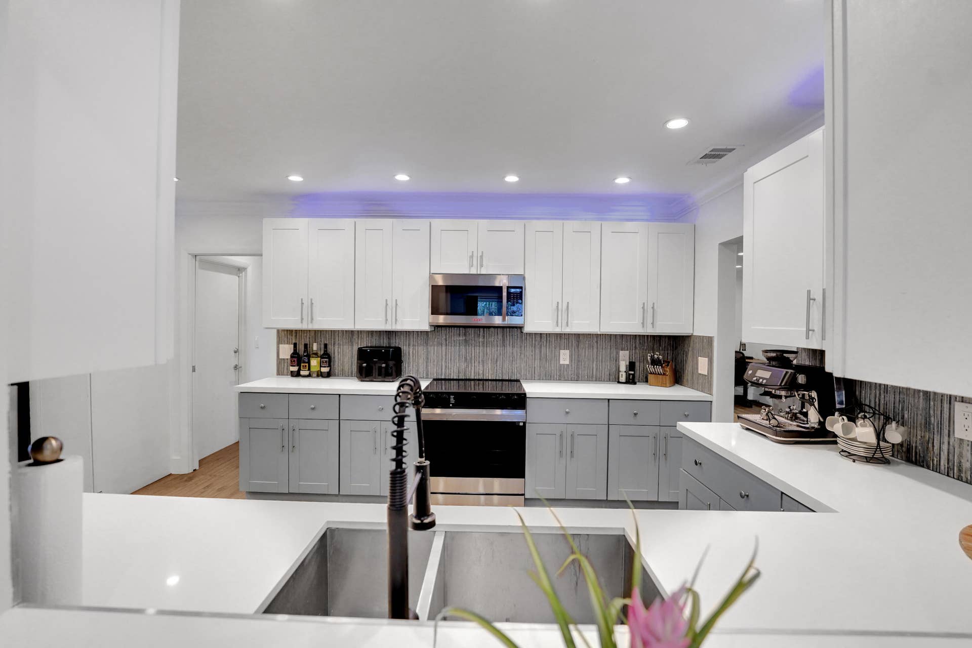380 NW 35TH Court, Oakland Park, FL 33309 Kitchen featuring two-tone cabinetry, white countertops, stainless steel appliances, recessed ceiling lighting, and a dual-basin stainless steel sink with a high-arch pull-down faucet