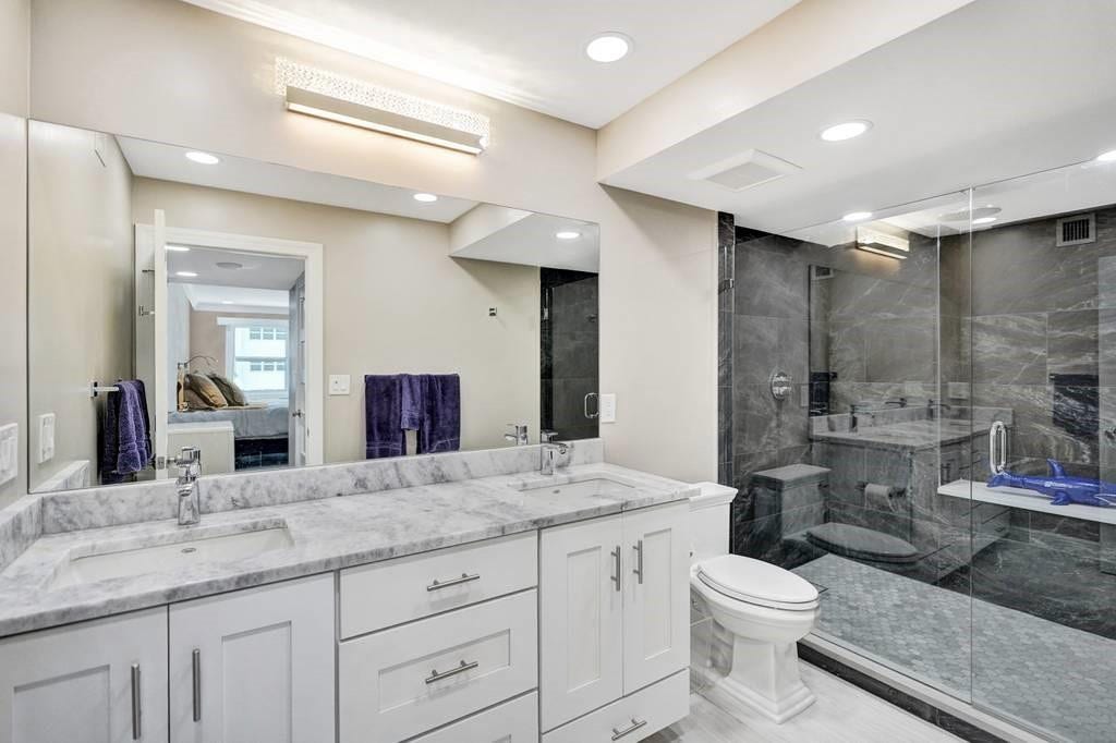 The elegant master bathroom has a quartz topped, double sink vanity, recessed lighting, and a beautiful Swarovski crystal light fixture. The faucet is Hansgrohe. The shower has been enlarged and has frameless glass doors and beautiful tile work.