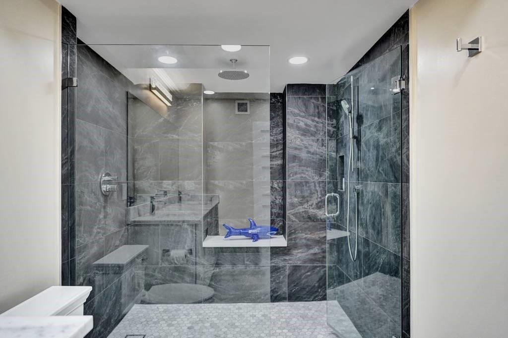This shower is extra large and has a rain forest shower head, frameless glass doors and beautiful tile work.