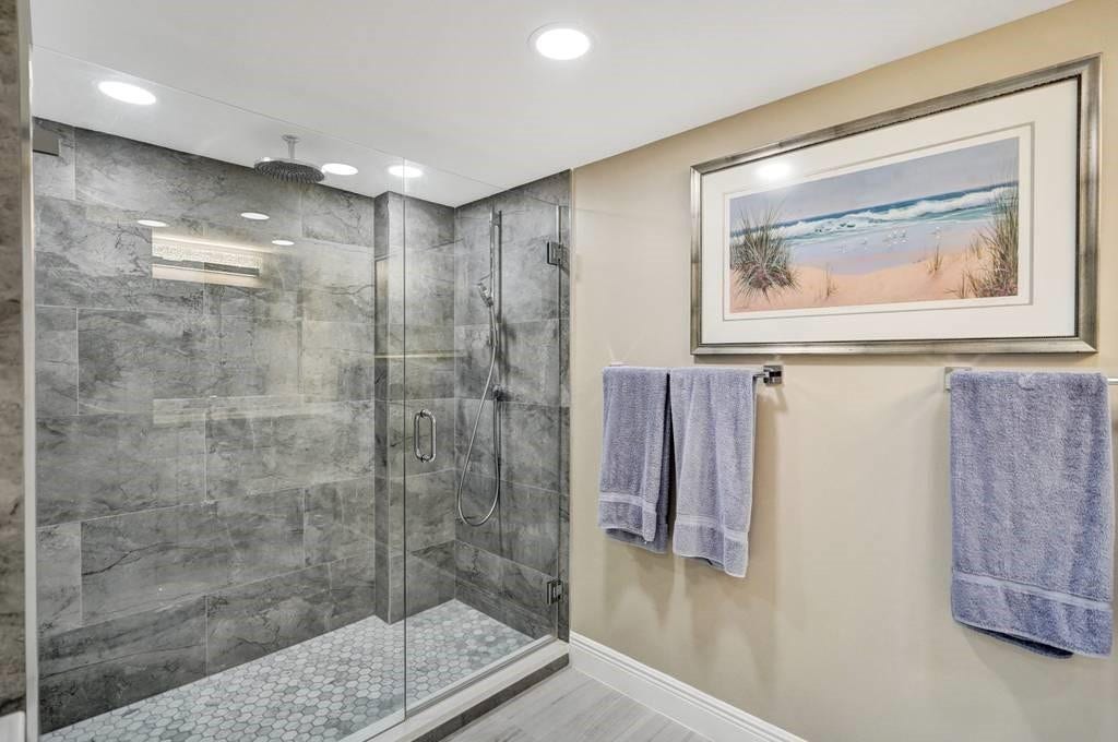 The second bathroom also features an extra large shower, with frameless glass doors and a rain shower fixture, as well as a quartz topped vanity, a Hansgrohe faucet and a Swarovski crystal light fixture.