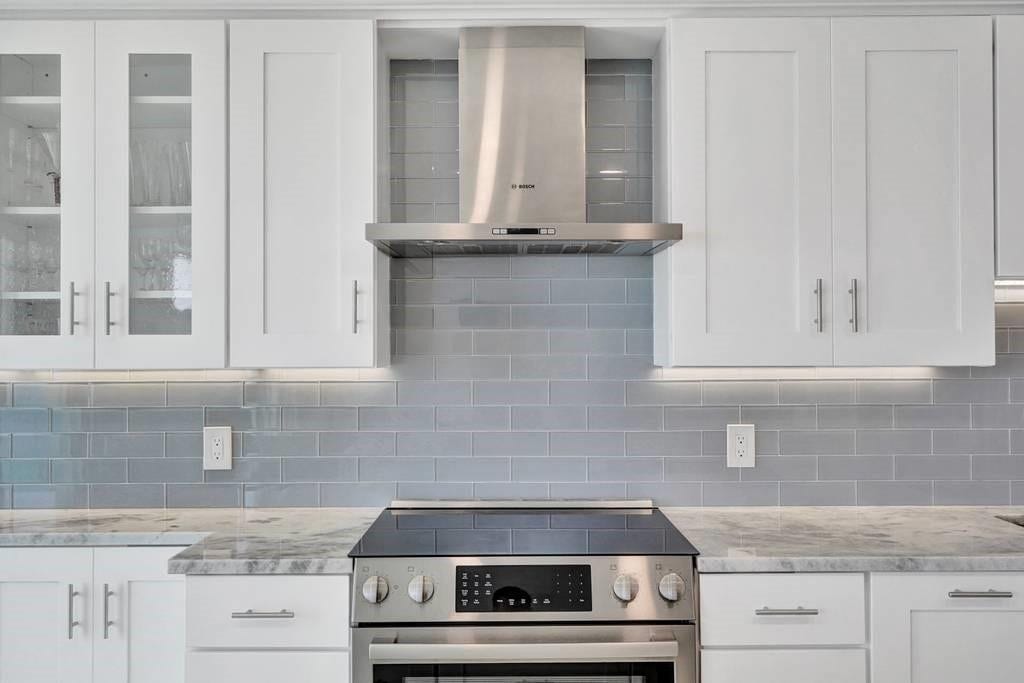 Beautiful glass subway tile backsplash. This is a Bosch stove and hood.