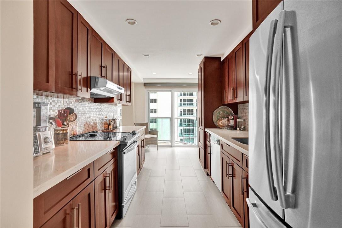 This beautiful kitchen has custom cabinets, stainless appliances, Ceasar stone countertops and a jazzy backsplash. The sliding glass doors lead out to the balcony. The wicker chair does not convey with the sale.