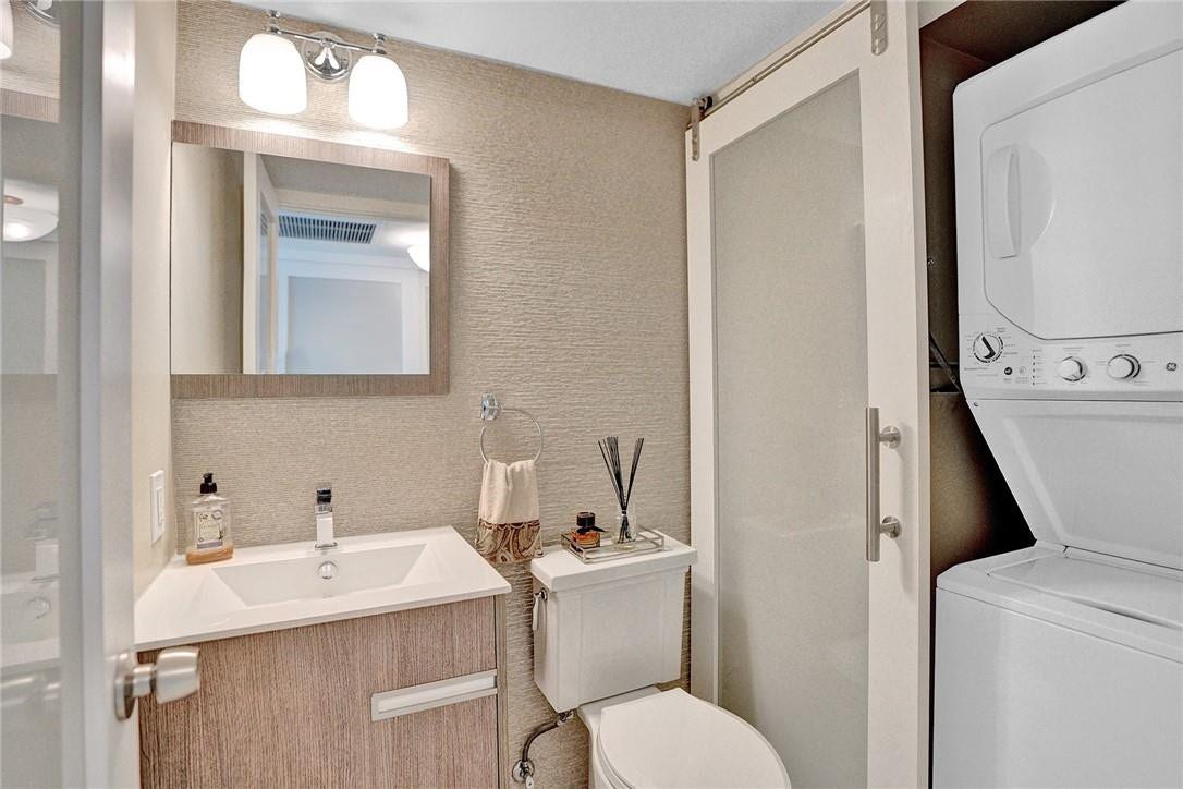 The washing machine and the dryer are housed behind a glass sliding door.