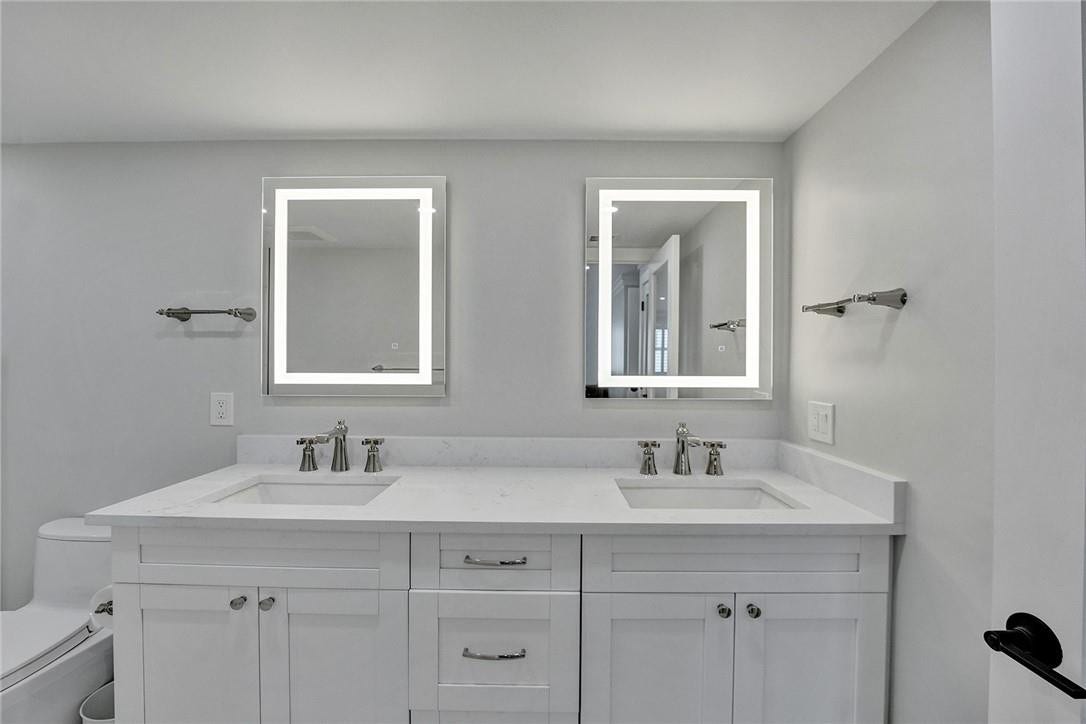 The owners widened the primary bath by one foot, and what a difference it makes. The vanity features illuminated mirrors, dual sinks, Moen faucets and hardware, and a quartz countertop.