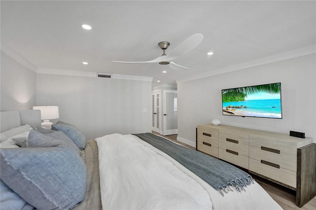 Along with the rest of this apartment, the primary bedroom has crown molding thru out. To the left of the tv, the open glass door leads out into the apartment. The other glass doors are a closet. The walk in closet is directly across from those two glass doors.