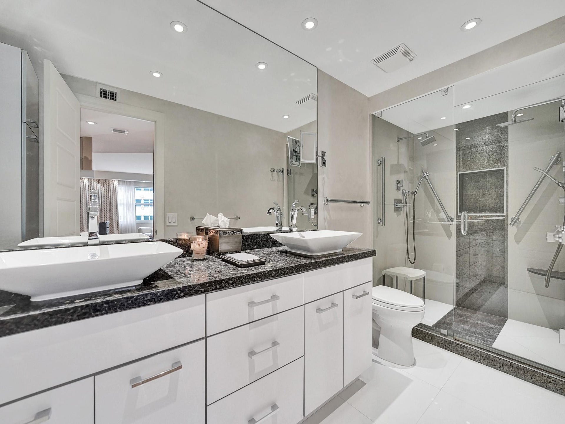 The primary bathroom has dual sinks, a custom vanity and a granite countertop.