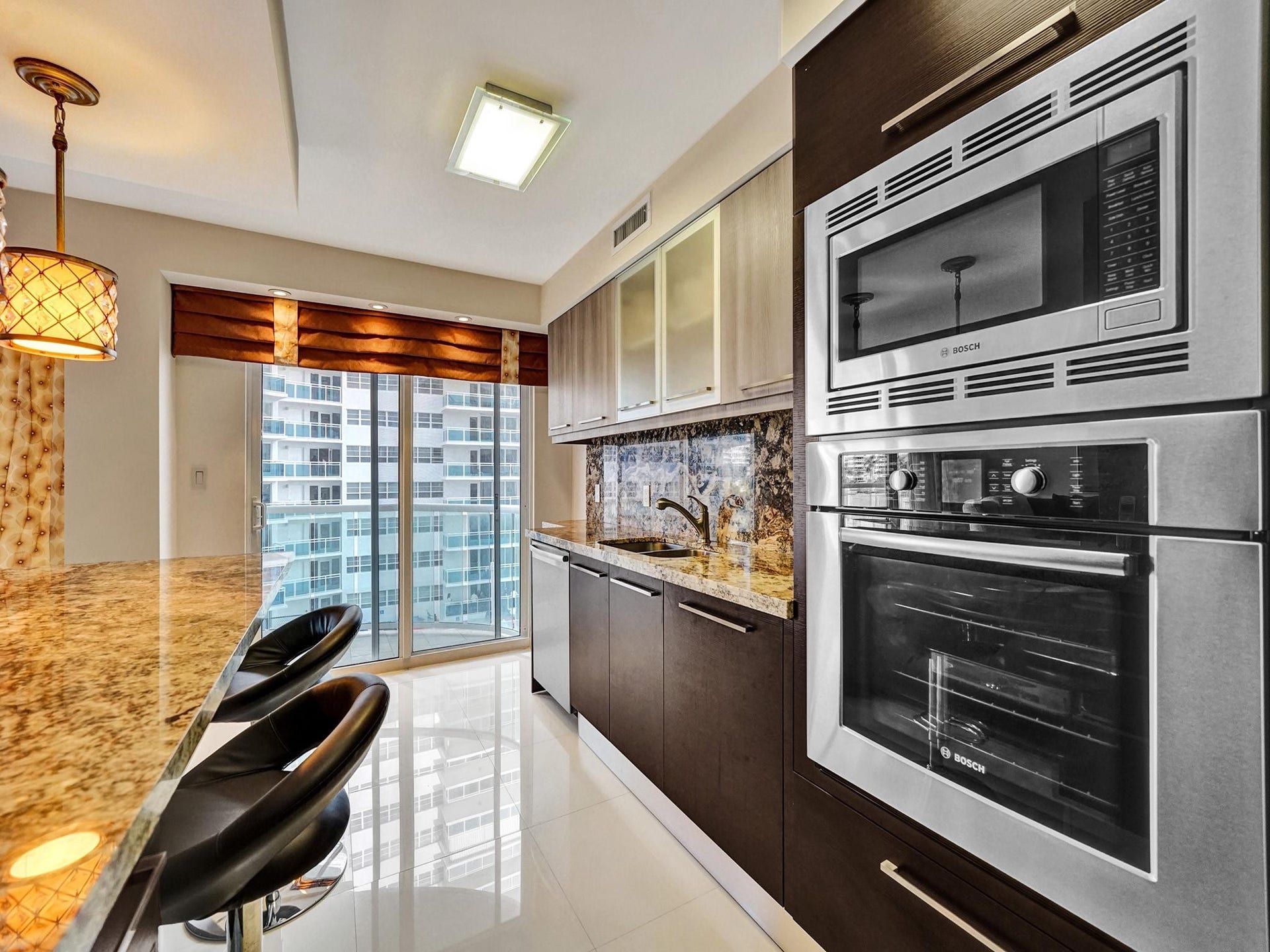 The kitchen has a custom made decorative valence and pleated shade, and it leads out to the balcony.