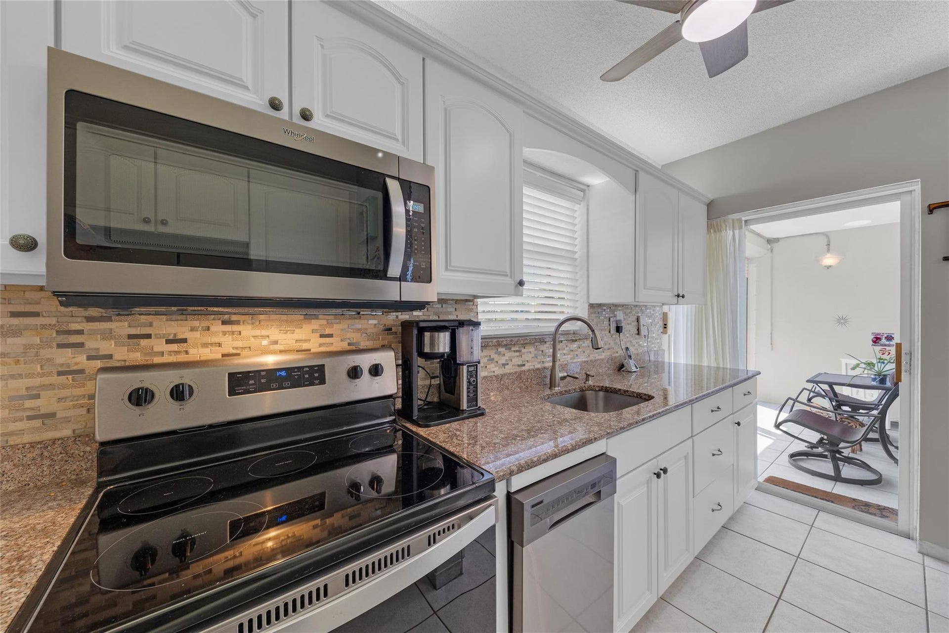 Kitchen offers white cabinets, stainless appliances, granite counters, tile backsplash and great natural light