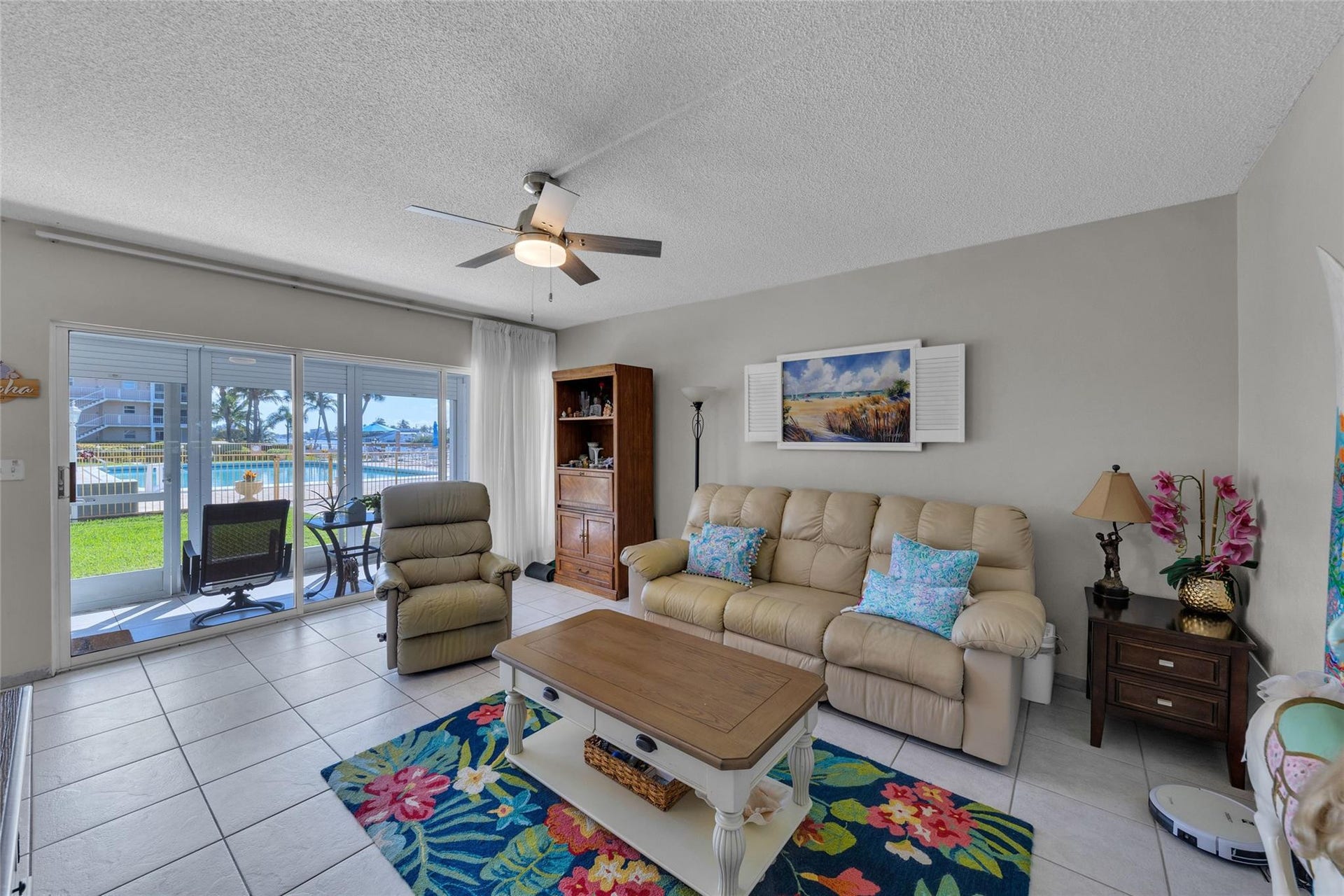 Spacious living room features great natural light, sliders to pool and water, tile flooring and overhead ceiling fan with lighting