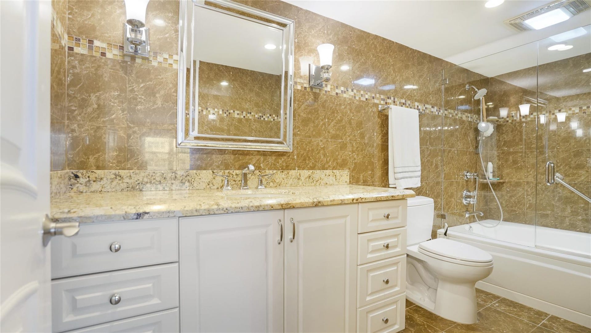 This beautiful primary bathroom has a granite topped vanity and a tub/shower.