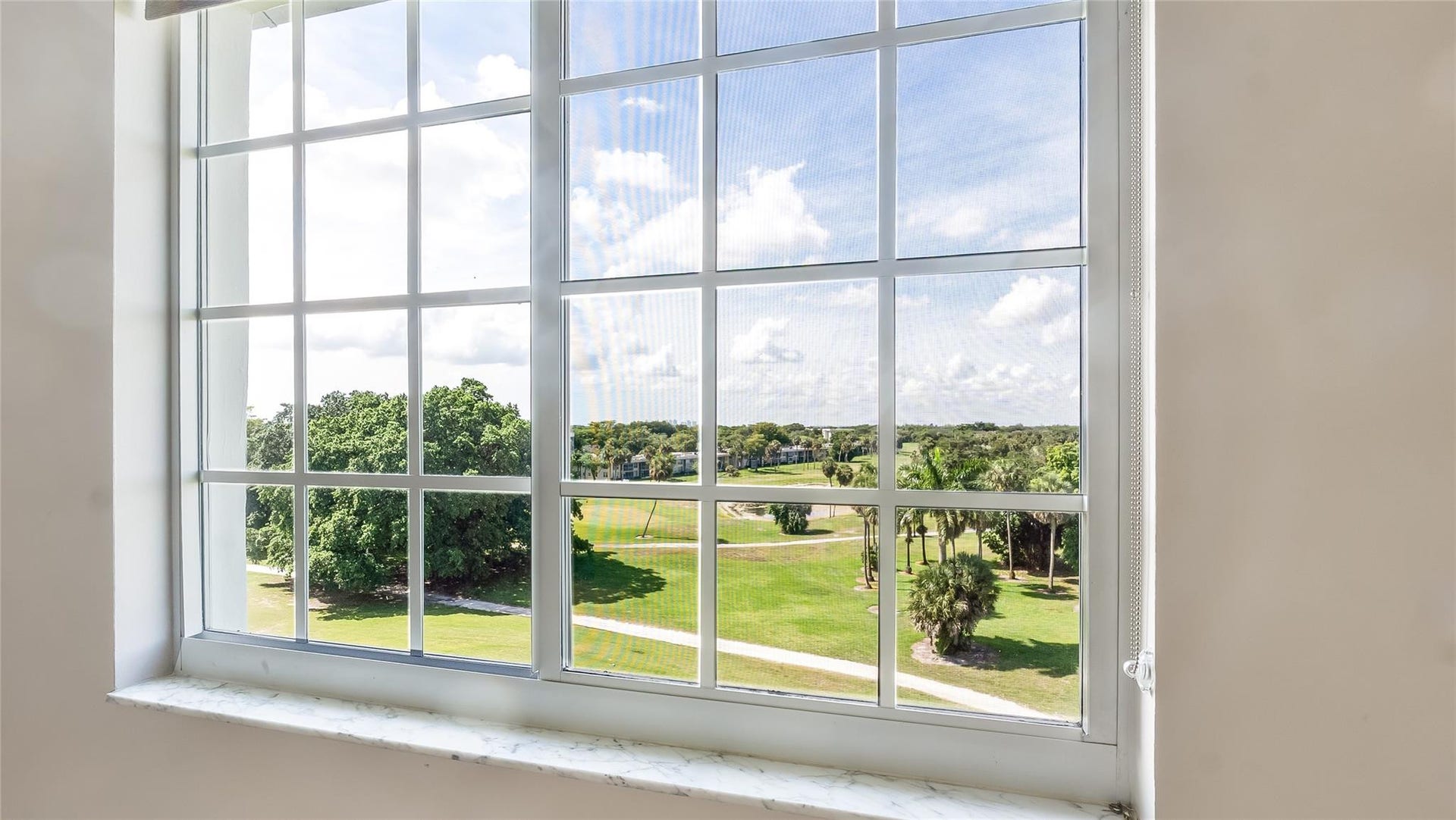 4116 W Palm Aire Drive, #166b, Pompano Beach, FL 33069 Primary Bed: Large picture window frames panoramic views of the lush fairways and palm-dotted landscape.