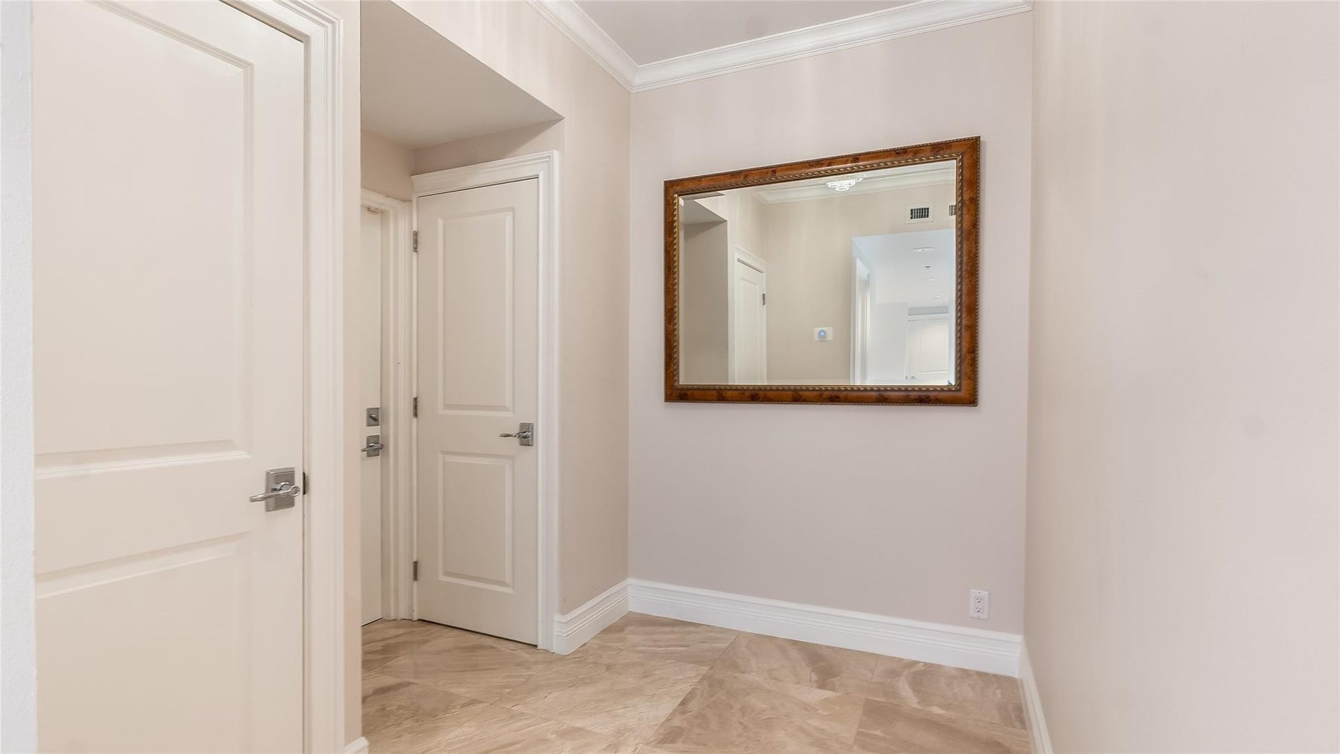 4116 W Palm Aire Drive, #166b, Pompano Beach, FL 33069 Welcoming entryway with neutral tones, crown molding, and a large wall mirror, offering a bright and elegant first impression.