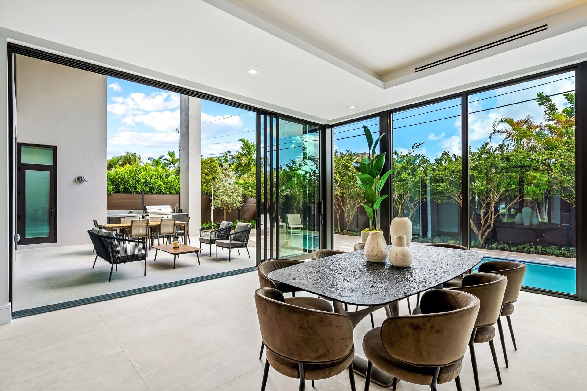 2000 Harbourview Drive, Fort Lauderdale, FL 33316 A light-filled dining area wrapped in floor-to-ceiling glass, offering seamless views of the lush garden and pool beyond. Modern and inviting, this elegant space is perfectly designed for effortless indoor-outdoor living and sophisticated entertaining.