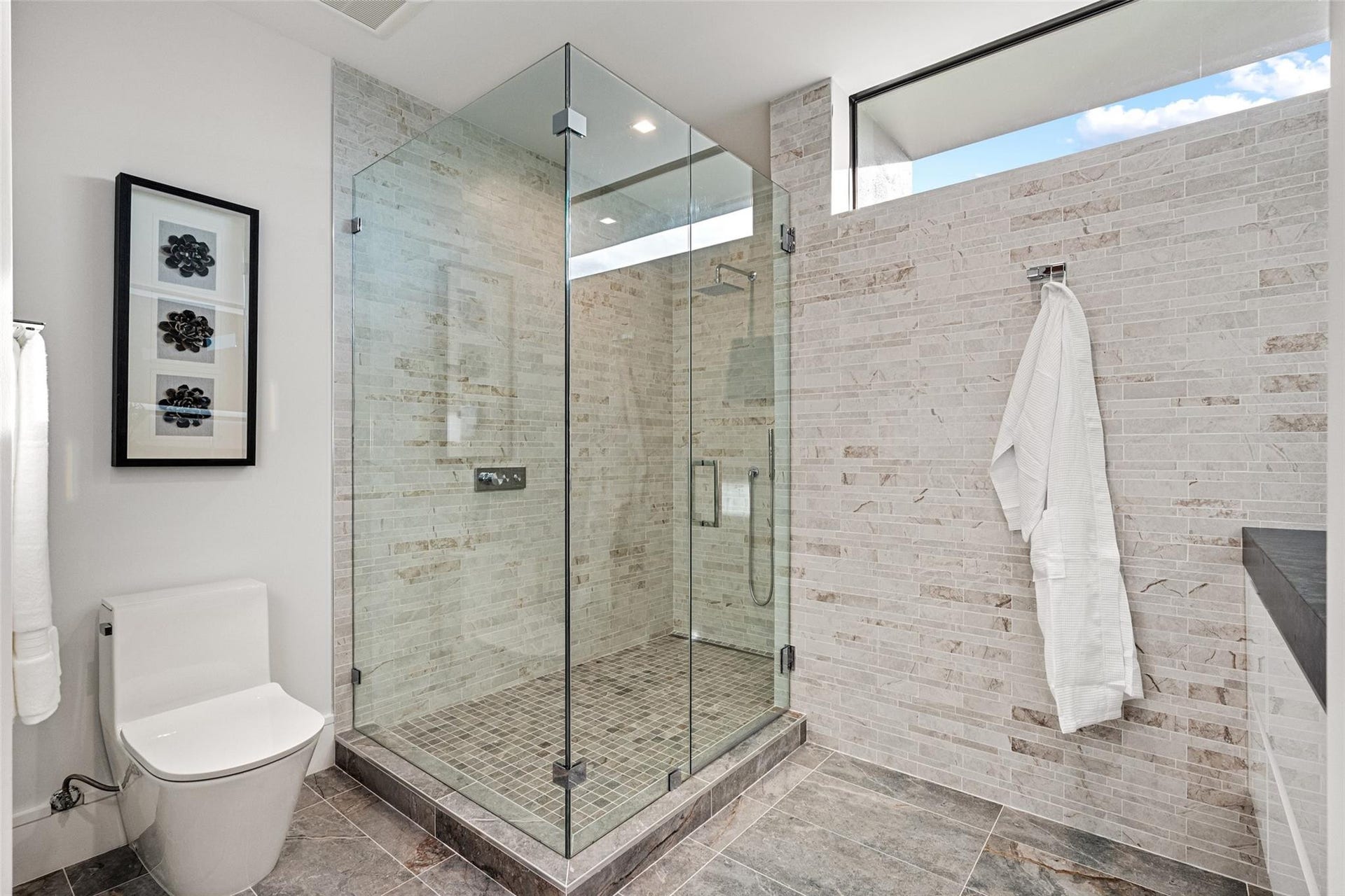 2000 Harbourview Drive, Fort Lauderdale, FL 33316 A bright, modern bath showcasing a glass-enclosed walk-in shower, sleek fixtures, and crisp neutral stone finishes. Clean-lined and thoughtfully appointed, this spa-inspired space offers comfort with contemporary sophistication.
