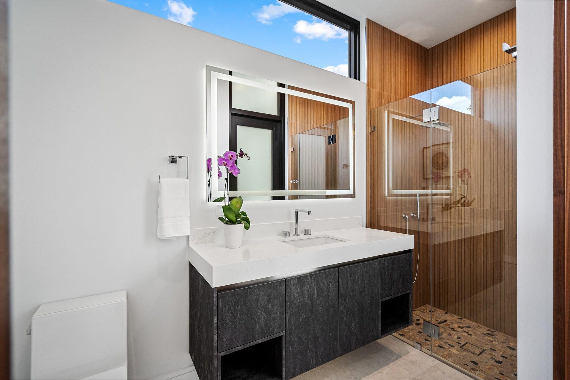 2000 Harbourview Drive, Fort Lauderdale, FL 33316 A sleek contemporary bath featuring a floating vanity with bold stone countertop, designer fixtures, and warm accent tones. Clean lines and modern finishes create a refined, spa-inspired retreat for guests.