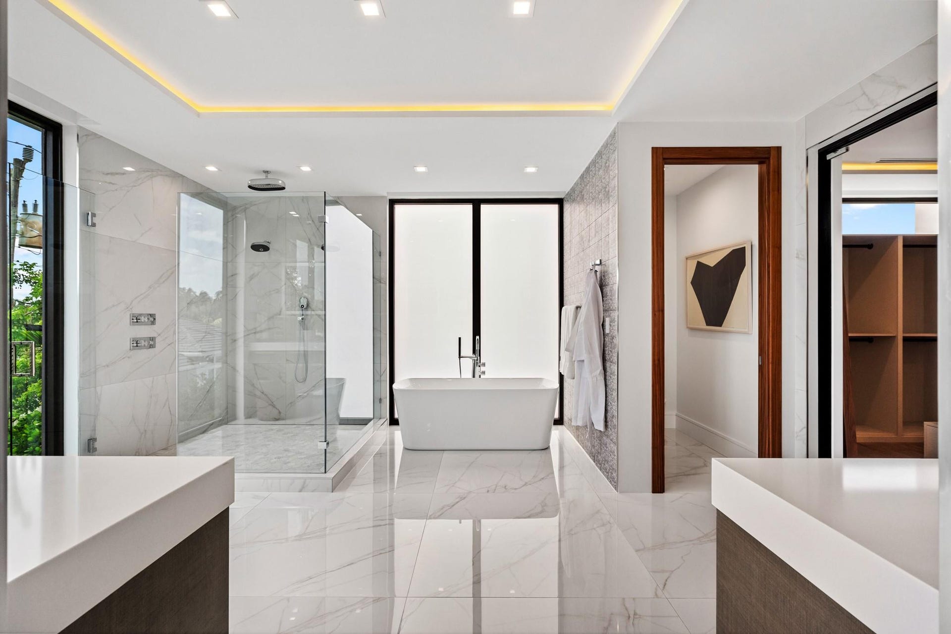 2000 Harbourview Drive, Fort Lauderdale, FL 33316 A spa-caliber primary bath featuring a freestanding soaking tub, expansive walk-in shower, and sleek floating vanities framed by warm wood accents. Light-filled and impeccably finished, this serene retreat embodies modern luxury and refined tranquility.