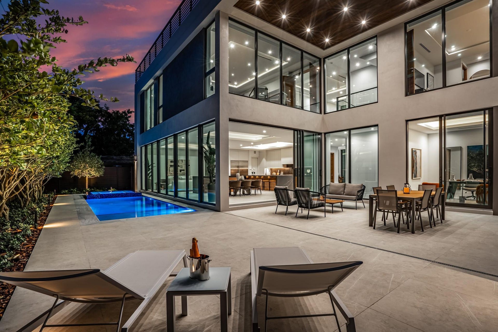 2000 Harbourview Drive, Fort Lauderdale, FL 33316 A breathtaking glass-wrapped courtyard illuminated at twilight, where soaring ceilings and expansive windows create a seamless indoor-outdoor experience. Refined lounge and dining spaces are beautifully positioned for sophisticated entertaining in a dramatic modern setting.