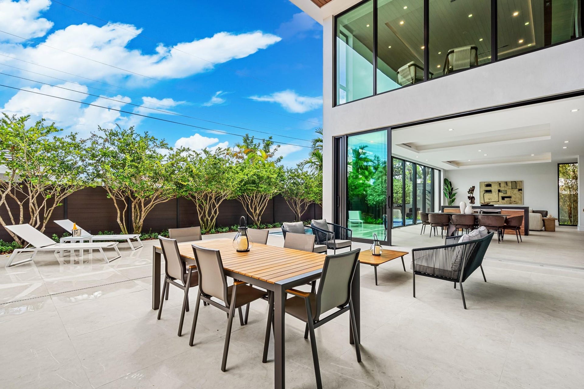 2000 Harbourview Drive, Fort Lauderdale, FL 33316 An expansive covered outdoor terrace designed for seamless entertaining, featuring a spacious dining area and comfortable lounge seating overlooking lush tropical landscaping. Modern and open, this inviting space extends the homes living areas into a private resort-style setting.