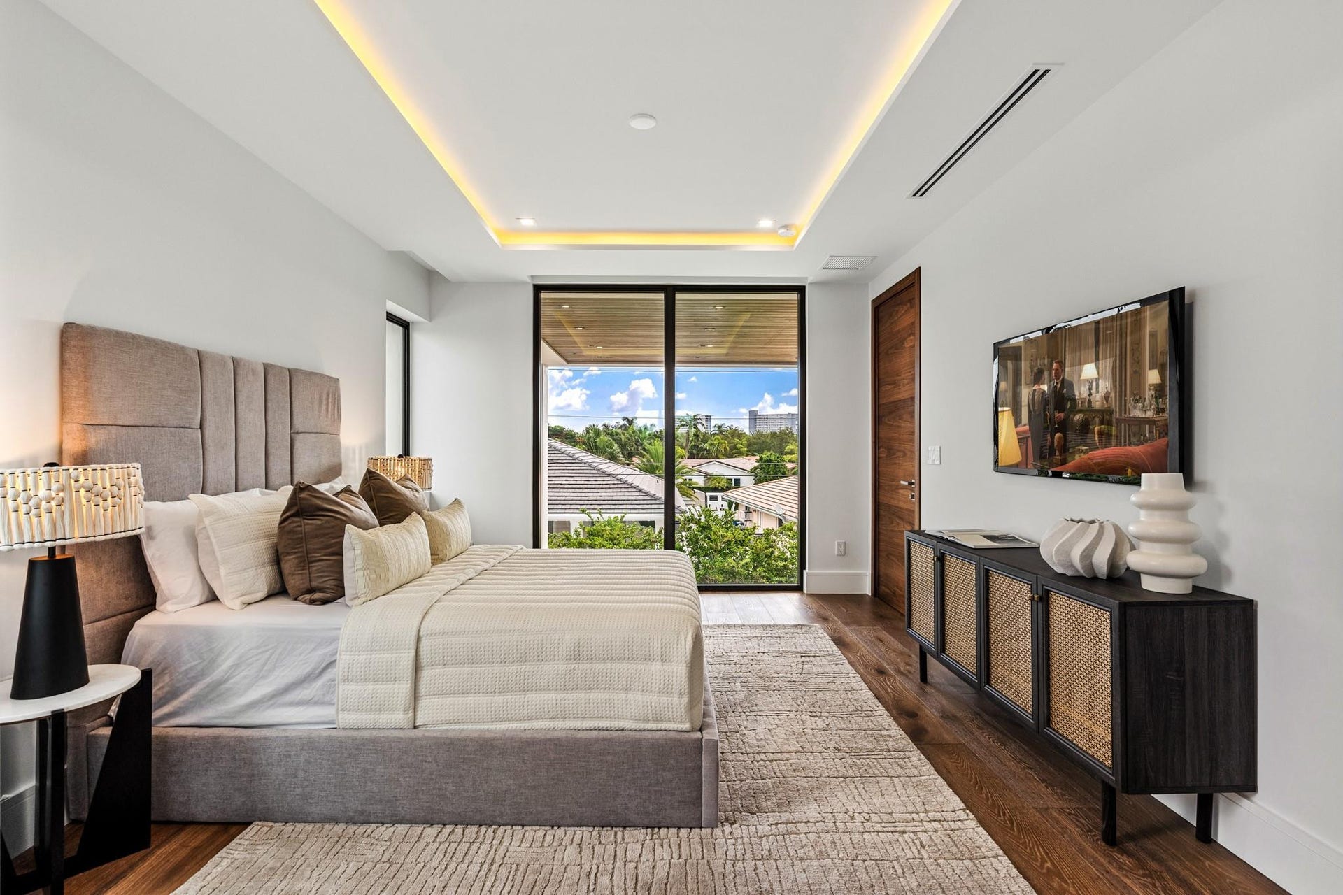 2000 Harbourview Drive, Fort Lauderdale, FL 33316 A refined modern bedroom retreat featuring custom ceiling detailing, warm wood accents, and expansive glass doors opening to lush outdoor views. Sophisticated and serene, this private sanctuary blends contemporary design with effortless indoor-outdoor living.
