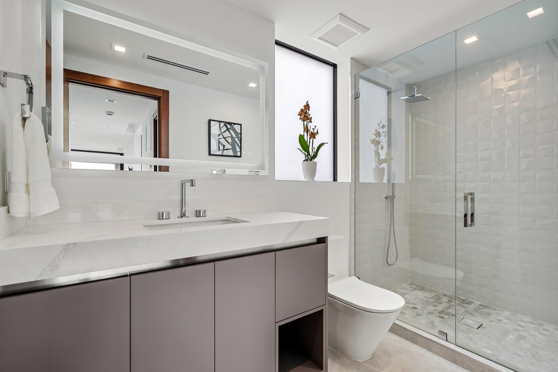2000 Harbourview Drive, Fort Lauderdale, FL 33316 A sleek contemporary bath featuring a streamlined floating vanity, expansive mirror, and crisp white finishes accented by warm wood tones. Clean, bright, and elegantly appointed, this spa-inspired space offers refined comfort with modern sophistication.