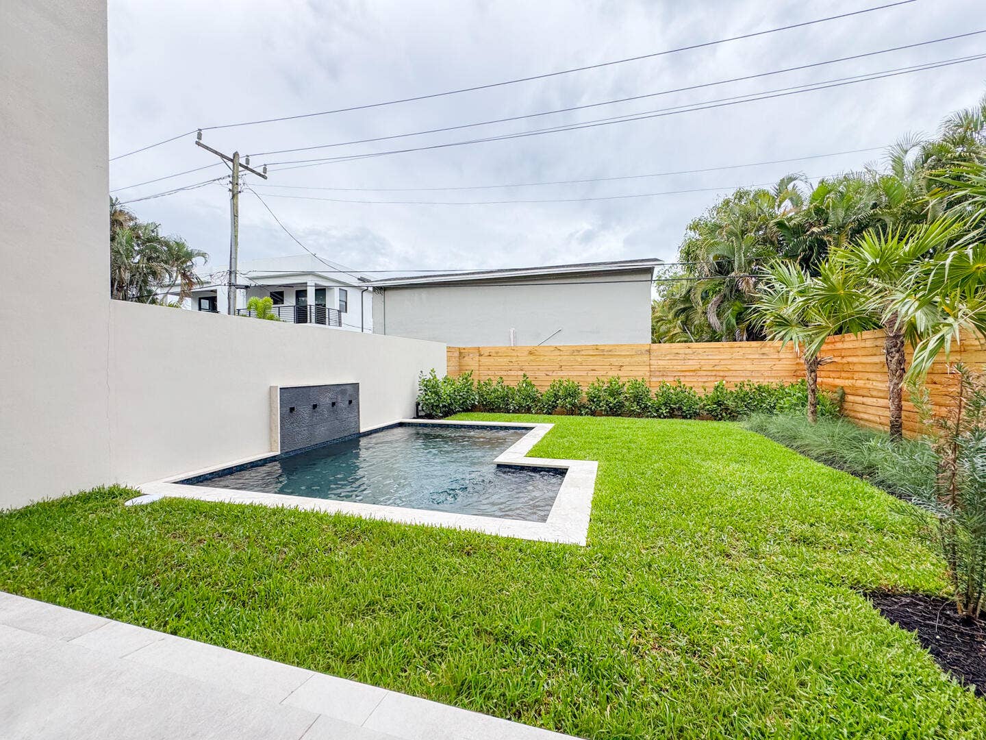 (as of April 8, 2026) view of spa pool and backyard from patio, clusia grows quickly and will be taller than fence by end of year
