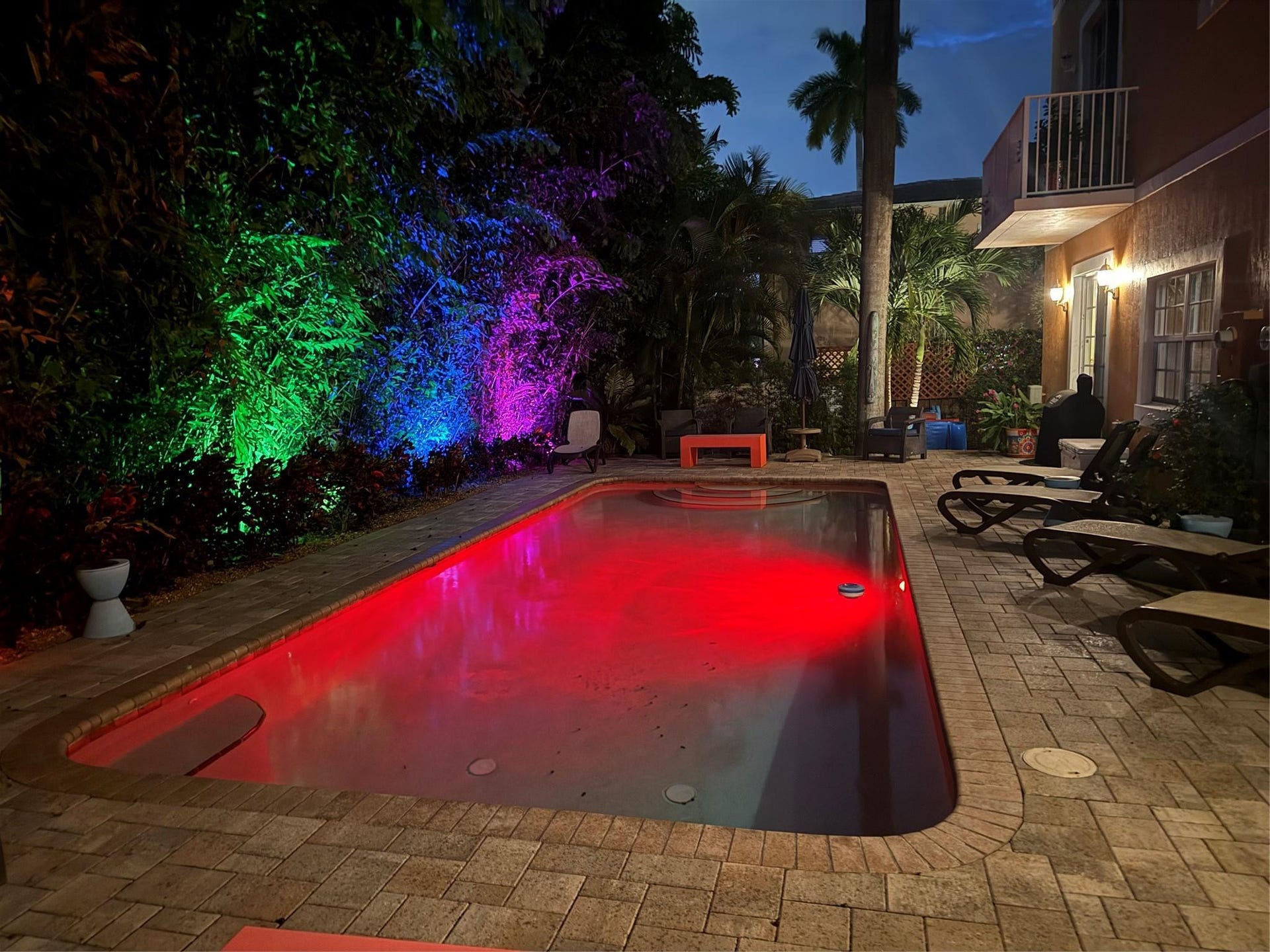 Pool illuminated at night with color-changing lights.
